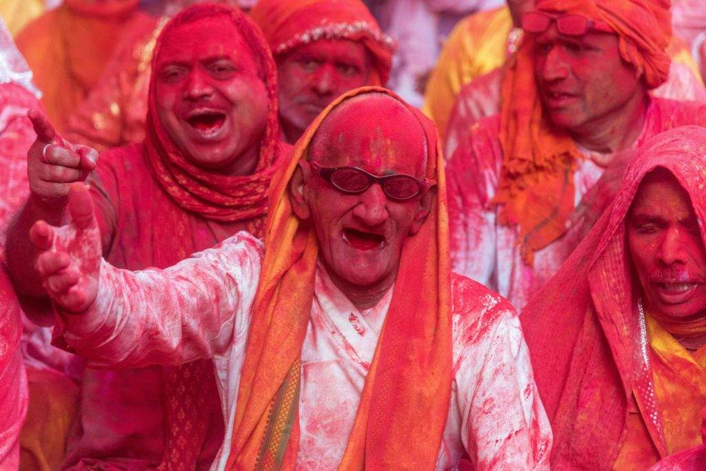 Indian villagers are covered in coloured powder during the Lathmar Holi festival at the Radha Rani temple in Barsana, some 130kms from New Delhi on March 16, 2016.  During the Lathmar Holi festival, the women of Barsana, the legendary hometown of Radha, consort of Hindu God Krishna, attack the men from Nandgaon, the hometown of Hindu God Krishna, with wooden sticks in response to their efforts to put color on them. / AFP PHOTO / François Xavier MARIT