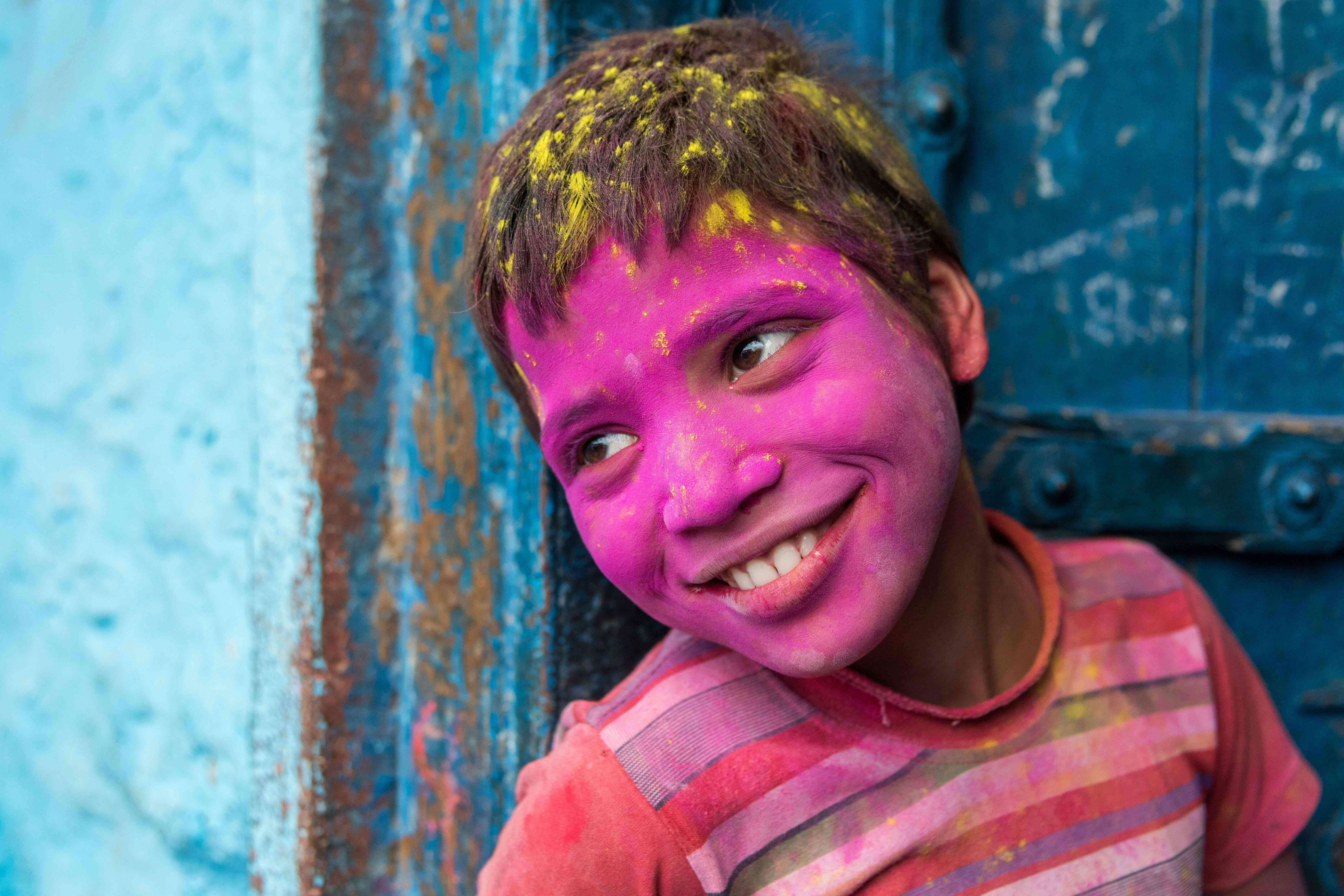 A young Indian reveller covered in coloured powder poses during the Lathmar Holi celebrations in the village of Barsana on March 17, 2016. holi, also called the Festival of Colours, is a popular Hindu spring festival observed in India at the end of the winter season on the last full moon day of the lunar month. / AFP PHOTO / FRANCOIS XAVIER MARIT