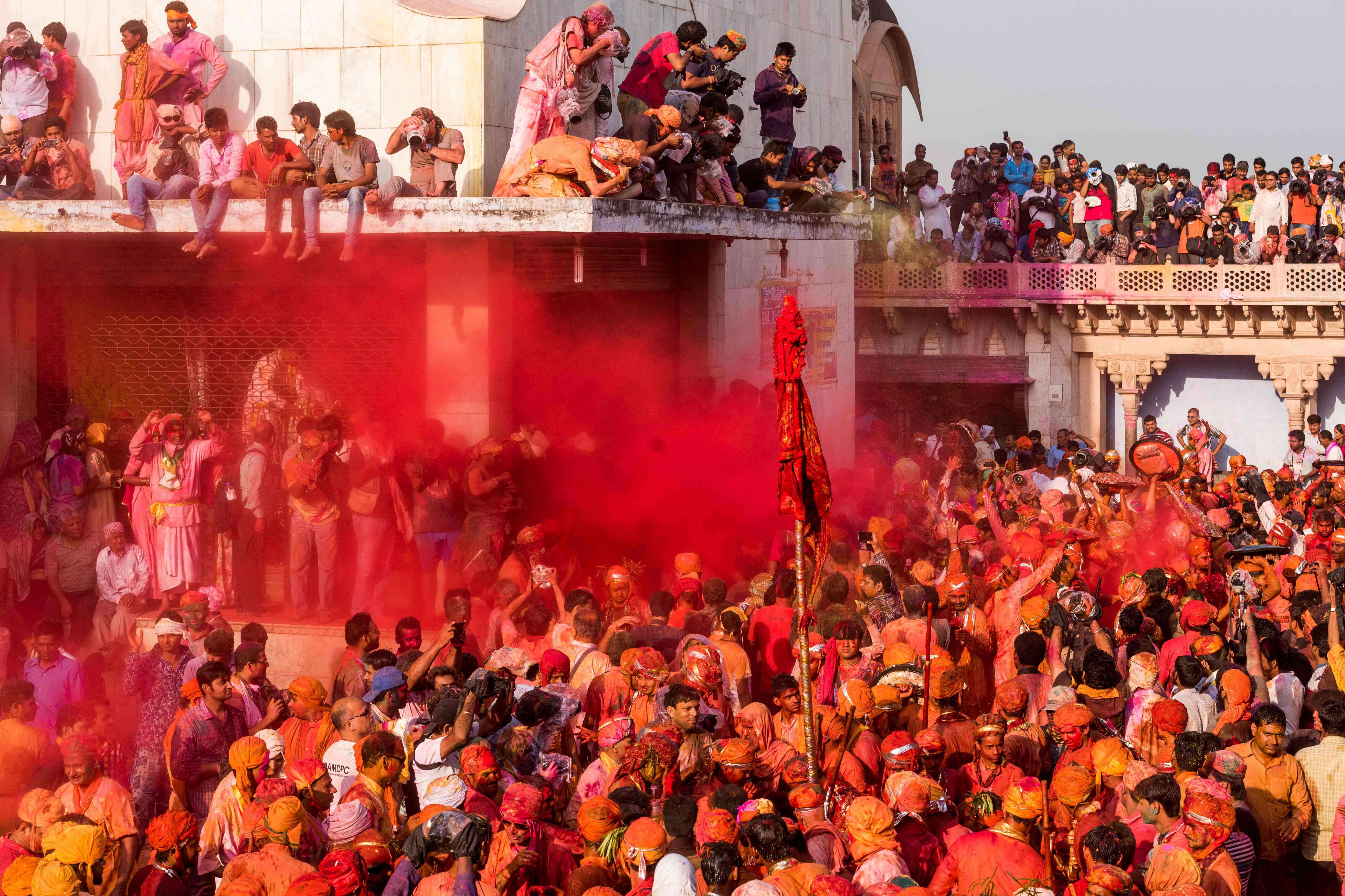Indian revellers throw red coloured powder onto villagers who are being sprayed with water  during the Lathmar Holi celebrations in the village of Nandgaon on March 18, 2016. holi, also called the Festival of Colours, is a popular Hindu spring festival observed in India at the end of the winter season on the last full moon day of the lunar month. / AFP PHOTO / Francois Xavier MARIT