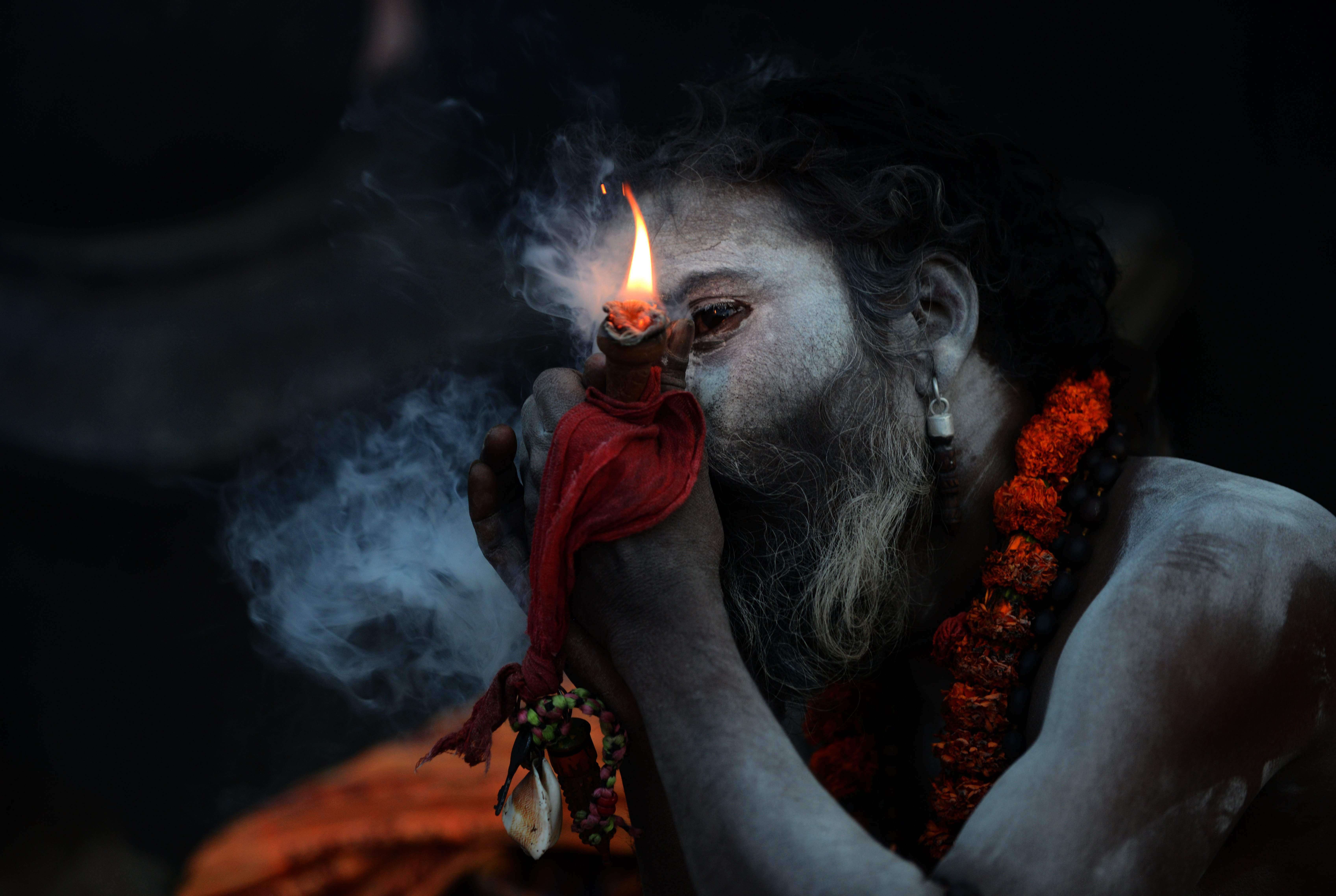 A Sadhu (Hindu holy man), smokes a chillum, a traditional clay pipe, as a holy offering to Lord Shiva, the Hindu god of creation and destruction near the Pashupatinath Temple in Kathmandu on March 6, 2016, on the eve of the Hindu festival Maha Shivaratri. Hindus mark the Maha Shivratri festival by offering special prayers and fasting. / AFP / PRAKASH MATHEMA