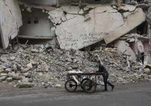 Aleppo, Syria --- Peddler passes in front of a destroyed building (Photo by Karam Almasri/NurPhoto) --- Image by © Karam Almasri/NurPhoto/Corbis