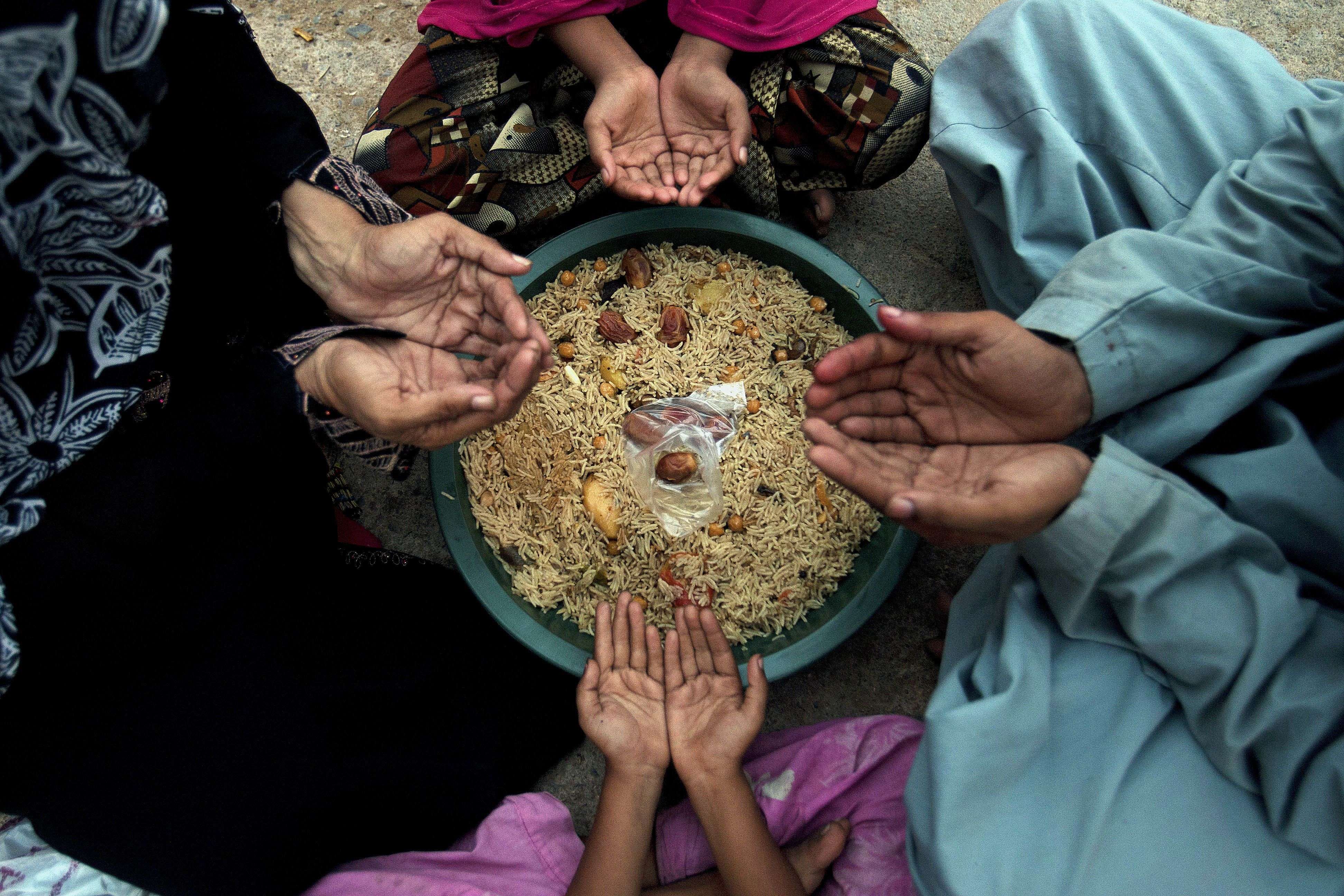 A family pray before breaking their fast during the Islamic month of Ramadan at a free food distribution point in Karachi, Pakistan, Wednesday, June 8, 2016. Muslims across the world are observing the holy fasting month of Ramadan, when they refrain from eating, drinking and smoking from dawn to dusk. (AP Photo/Shakil Adil)