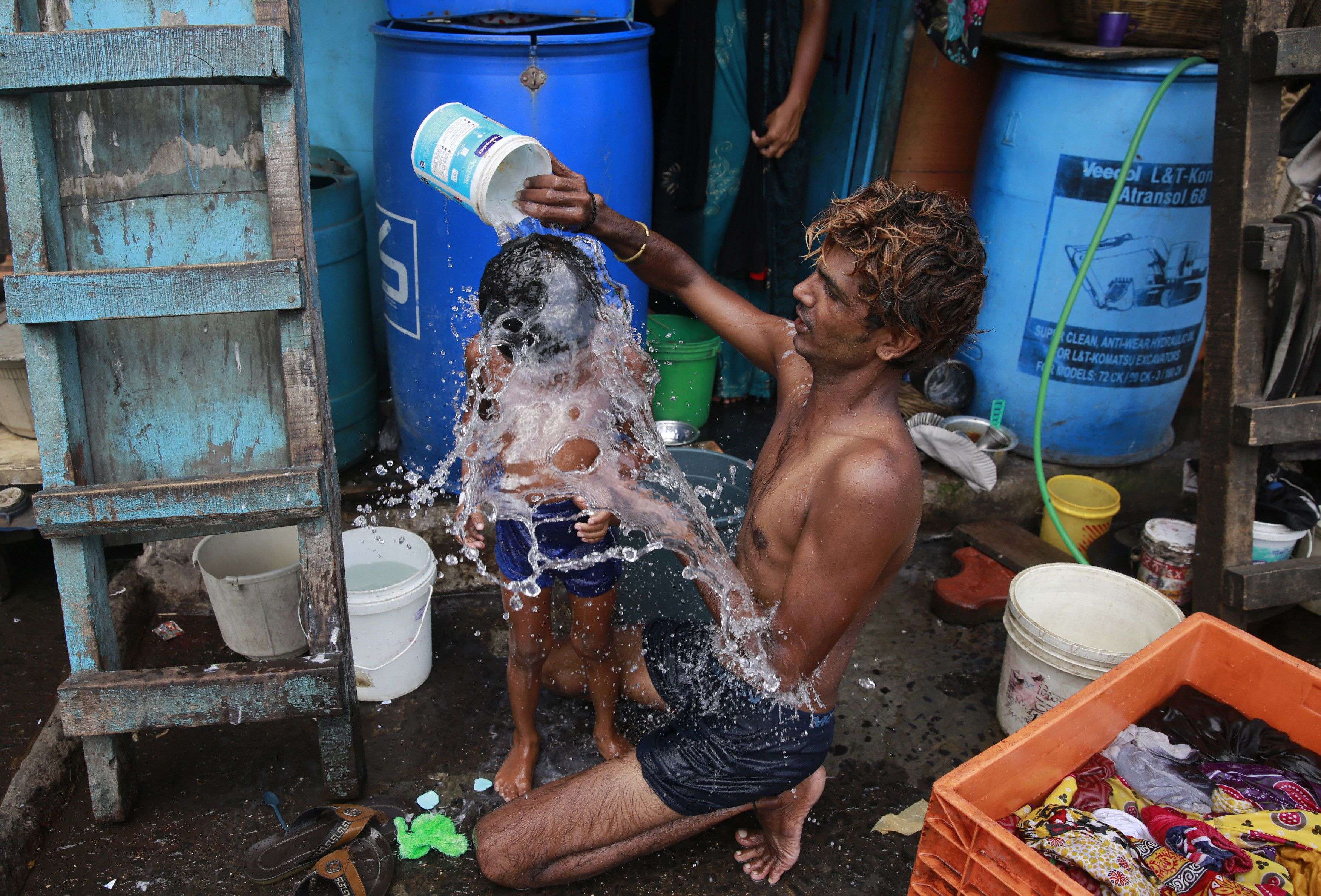 A man bath his son on a hot afternoon in a slum in Mumbai, India, Monday, May 23, 2016. Authorities in a parched western Indian state sprinkled water in the streets and awaited the arrival of a special water train on Saturday, two days after temperatures reached a record-high 51 degrees Celsius (124 Fahrenheit). (AP Photo/Rafiq Maqbool)