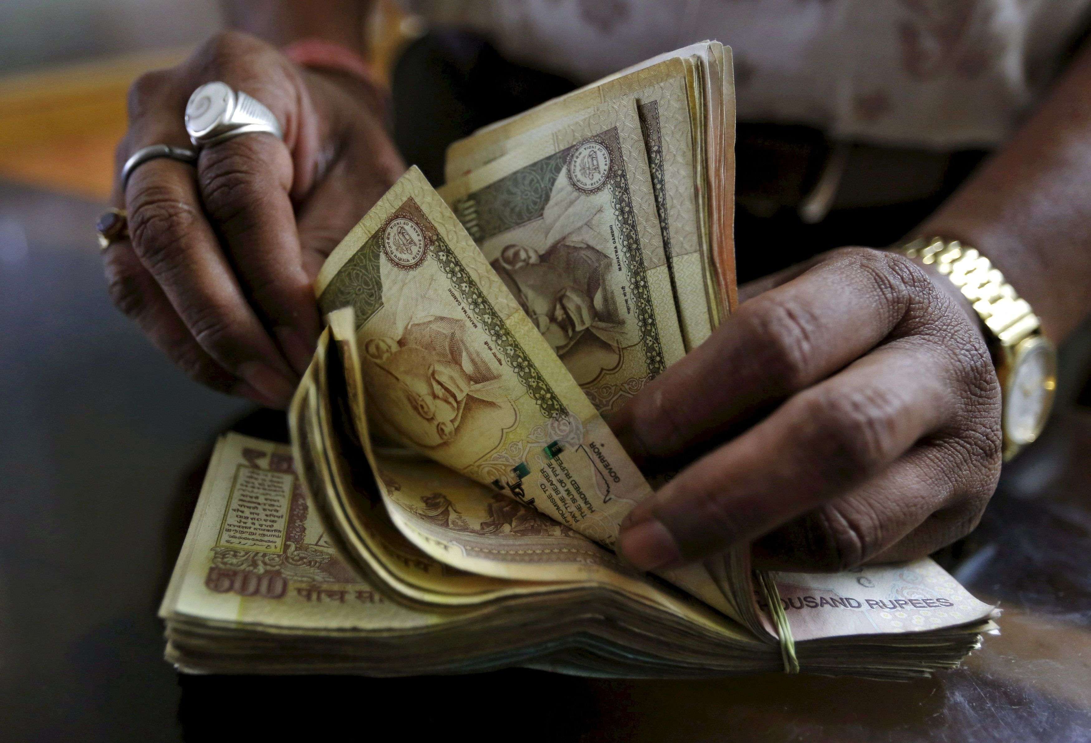 A money lender counts Indian rupee currency notes at his shop in Ahmedabad, India, May 6, 2015. REUTERS/Amit Dave/File Photo