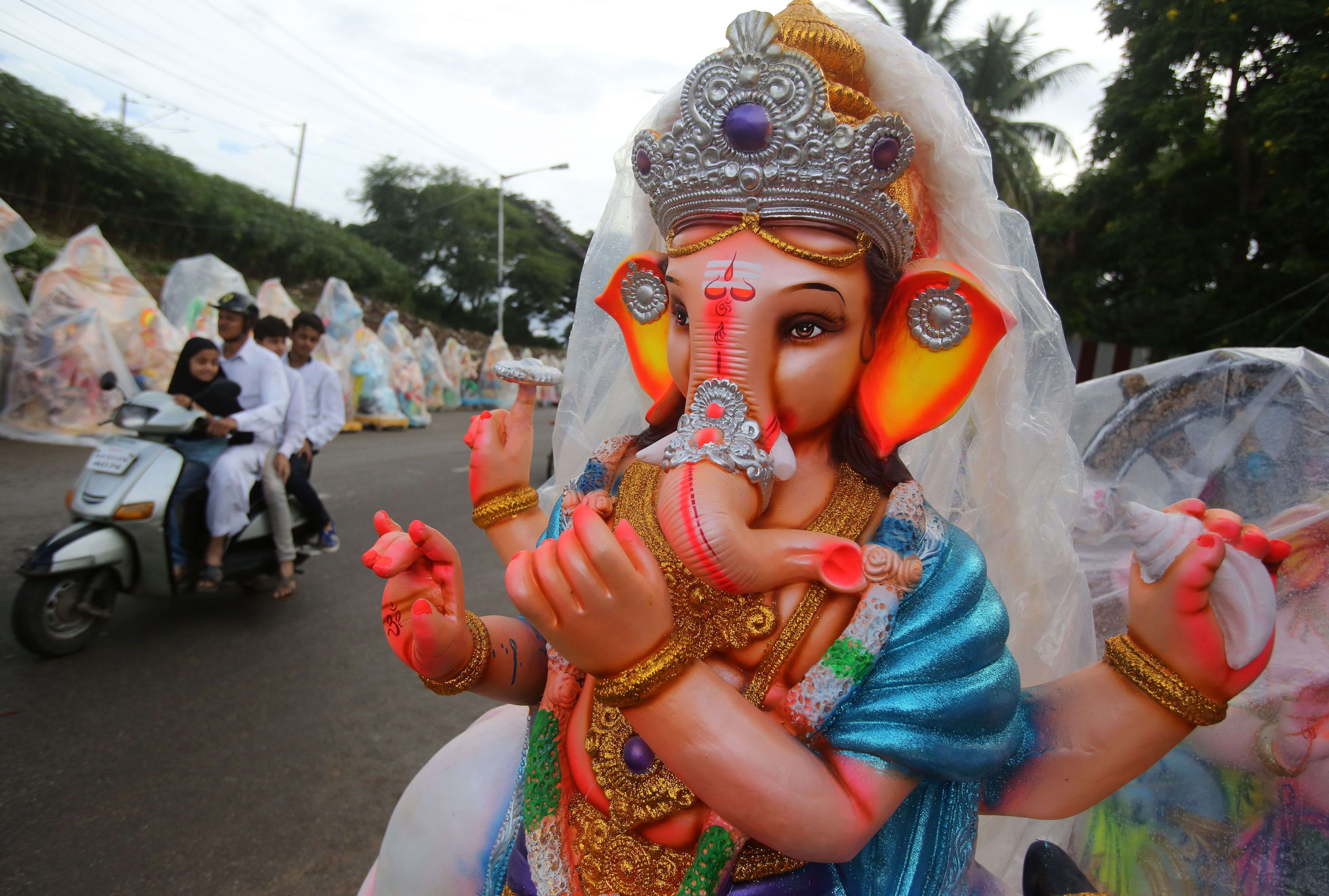 An Indian Muslim family rides past an idol of elephant-headed Hindu god Ganesha, put up on display to be sold ahead of Ganesh Chaturthi festival in Bangalore, India, Friday, Sept. 2, 2016. After worshipping the idols in their homes or specially set up worship venues, devotees immerse them in water bodies at the end of the festival. (AP Photo/Aijaz Rahi)