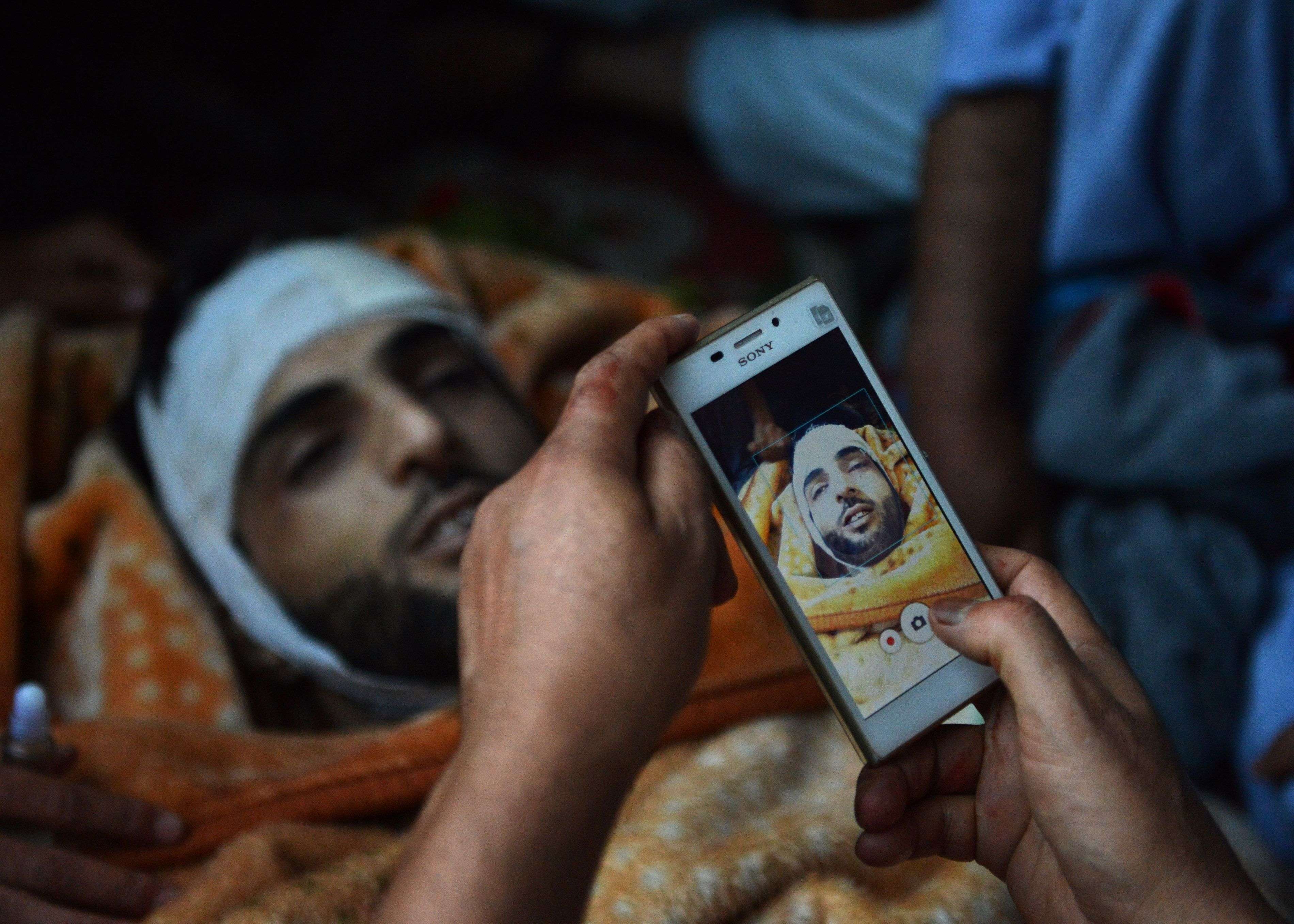 (FILES) In this photograph taken on July 9, 2016, Kashmiri mourners take photographs of the body of Burhan Muzaffar Wani, the new-age poster boy for the rebel movement in the restive Himalayan state of Jammu and Kashmir, ahead of his funeral in Tral, his native town, 42kms south of Srinagar. Burhan Wani was part of a new generation of young, educated Kashmiri militants using social media to spread their demands for independence from Indian rule, turning growing Internet use in the restive region into a powerful recruiting tool. Wani, whose death in a shoot-out with government forces has triggered deadly clashes with protesters in Indian Kashmir, was the son of a headmaster who excelled at school before he left home aged just 15 to join the region's largest rebel group. / AFP PHOTO / TAUSEEF MUSTAFA