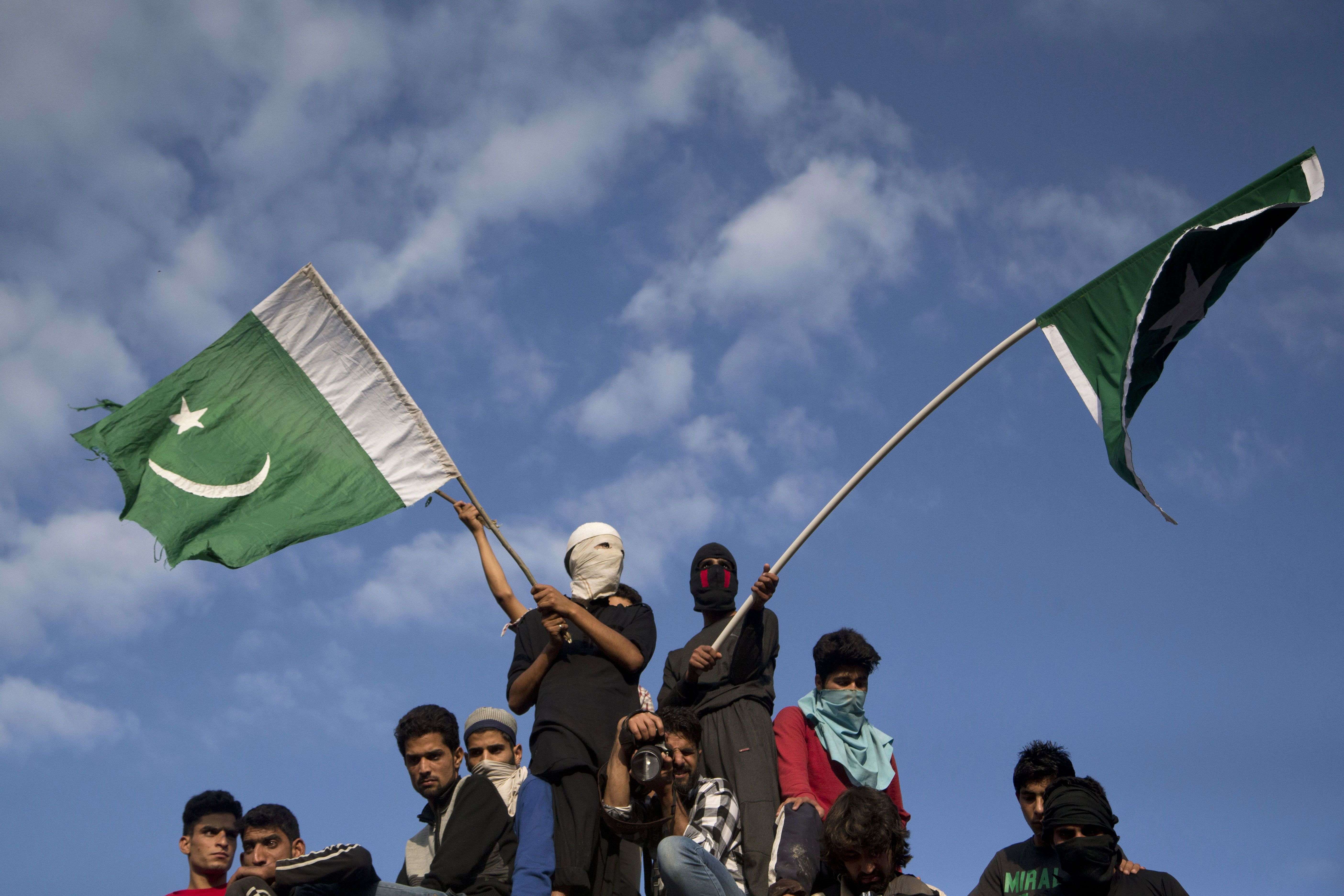 FILE- In this July 9, 2016 file photo, Kashmiri villagers wave Pakistani flags during the funeral procession of Burhan Wani, chief of operations of Indian Kashmir's largest rebel group Hizbul Mujahideen, in Tral, some 38 Kilometers (24 miles) south of Srinagar, Indian controlled Kashmir. When Indian forces gleefully announced last week that they had killed a top Kashmiri rebel leader, they called it a major victory in the fight against militants in the disputed Himalayan region. They clearly didn’t expect the backlash that followed - an outpouring of public anger, daily protests and dozens dead in the streets. (AP Photo/Dar Yasin, File)