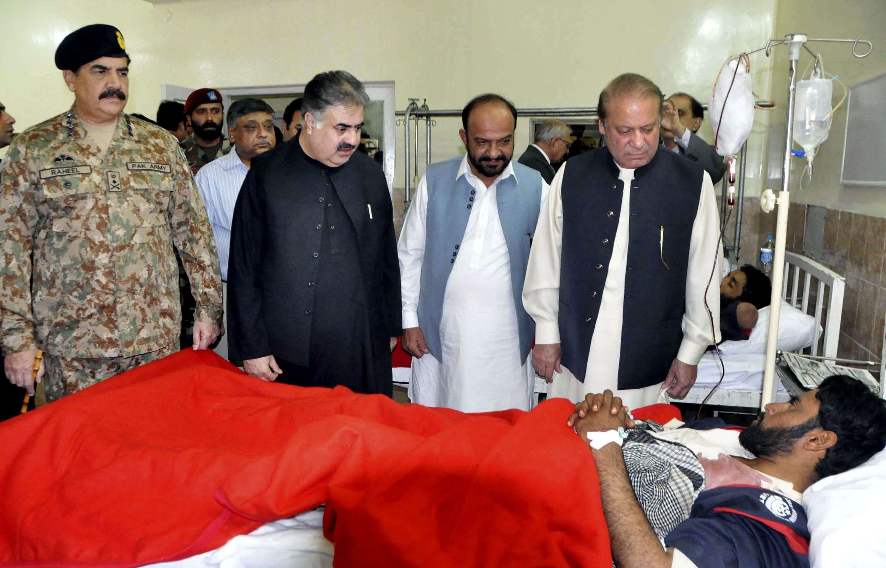 In this photo provided by Pakistan's Press Information Department, Pakistan's Prime Minister Nawaz Sharif, right, talks to a survivor of an overnight attack on the Police Training Academy, with Pakistan army chief Gen. Raheel Sharif, left, at a local hospital in Quetta, Pakistan, Tuesday, Oct. 25, 2016. Militants wearing suicide vests stormed a Pakistani police academy in the southwestern city of Quetta overnight, killing dozens of people, mostly police cadets and recruits, and waging a ferocious gun battle with troops that lasted into early hours Tuesday. (AP Photo/Press Information Department)