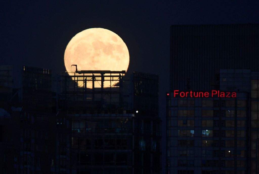 A 'supermoon' rises behind the skyline of Beijing. (AFP PHOTO / GREG BAKER)