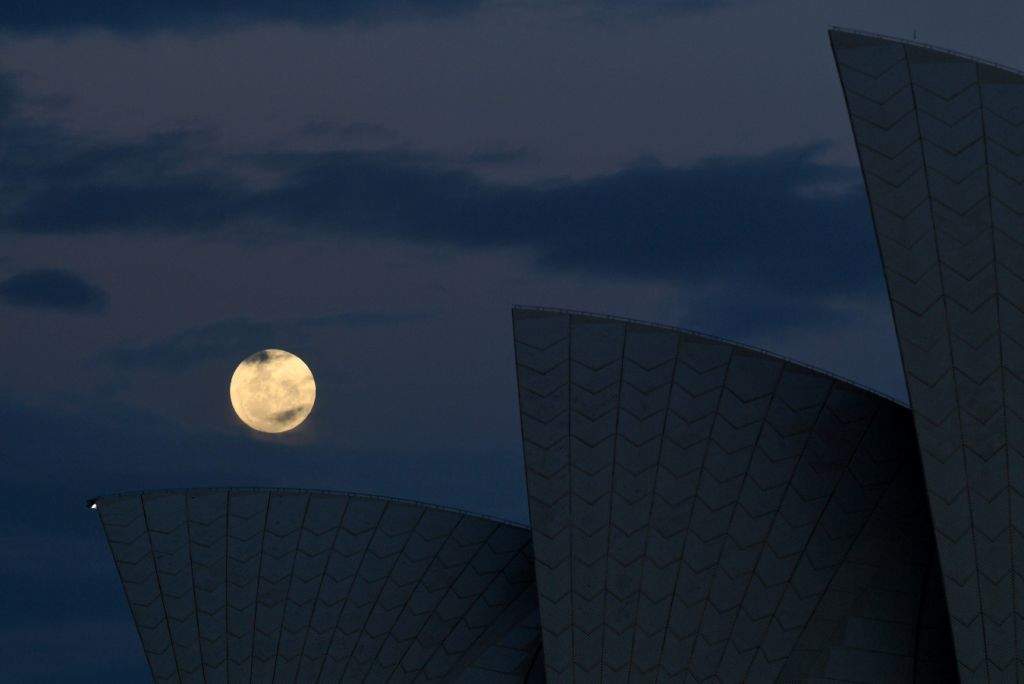 The 'supermoon' rises over the sails of the Sydney Opera House. (AFP PHOTO / WILLIAM WEST)