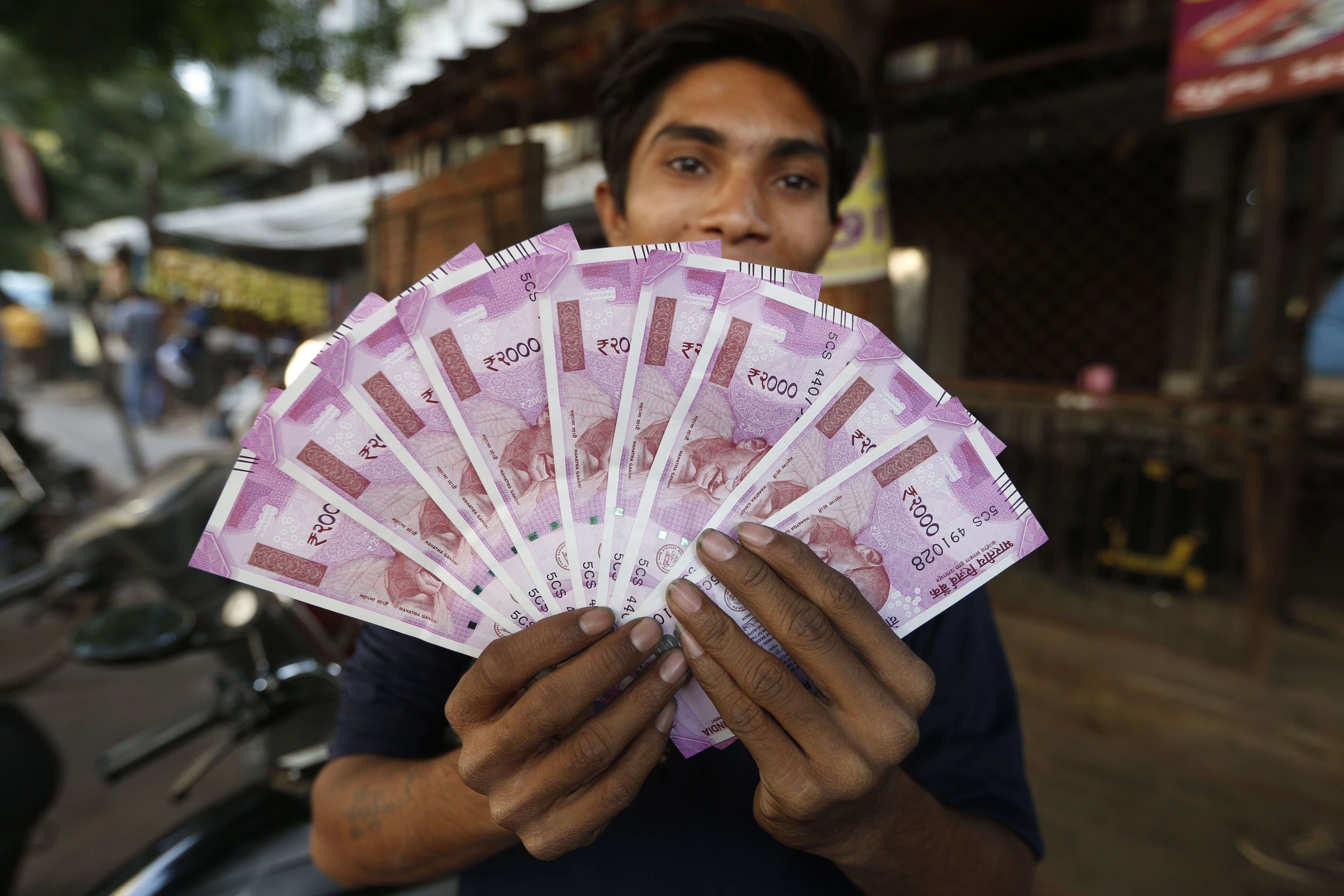 FILE - In this Nov. 11, 2016 file photo, an Indian man displays new currency notes of 2000 Indian rupee in Ahmadabad, India. The sudden withdrawal of 86 percent of India's currency has left cash in short supply, retail sales stumbling and wholesale markets in turmoil. (AP Photo/Ajit Solanki, File)