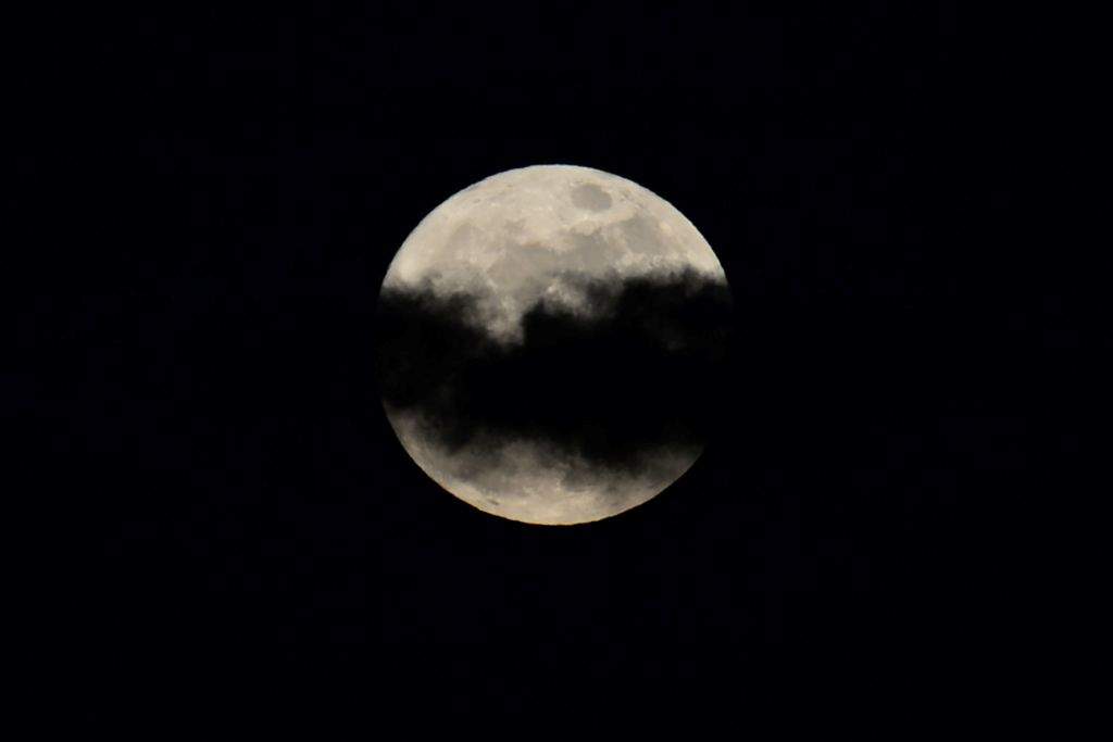The 'supermoon' is seen partially obscured by clouds over Manila. (AFP PHOTO / TED ALJIBE) 