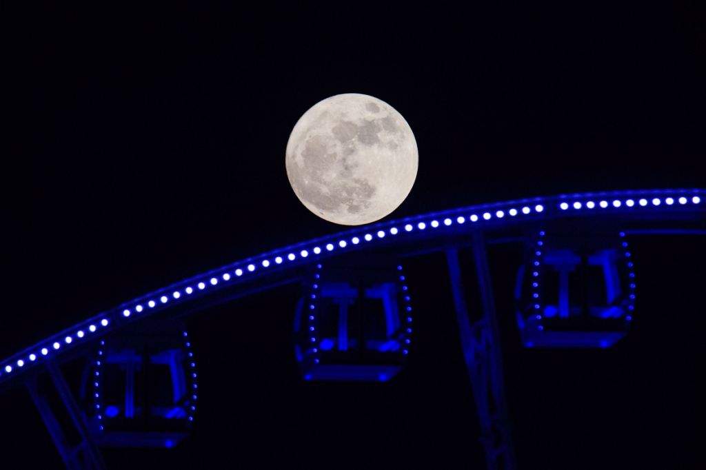 A 'supermoon' is seen rising beyond a ferris wheel in Hong Kong. (AFP PHOTO / ANTHONY WALLACE)