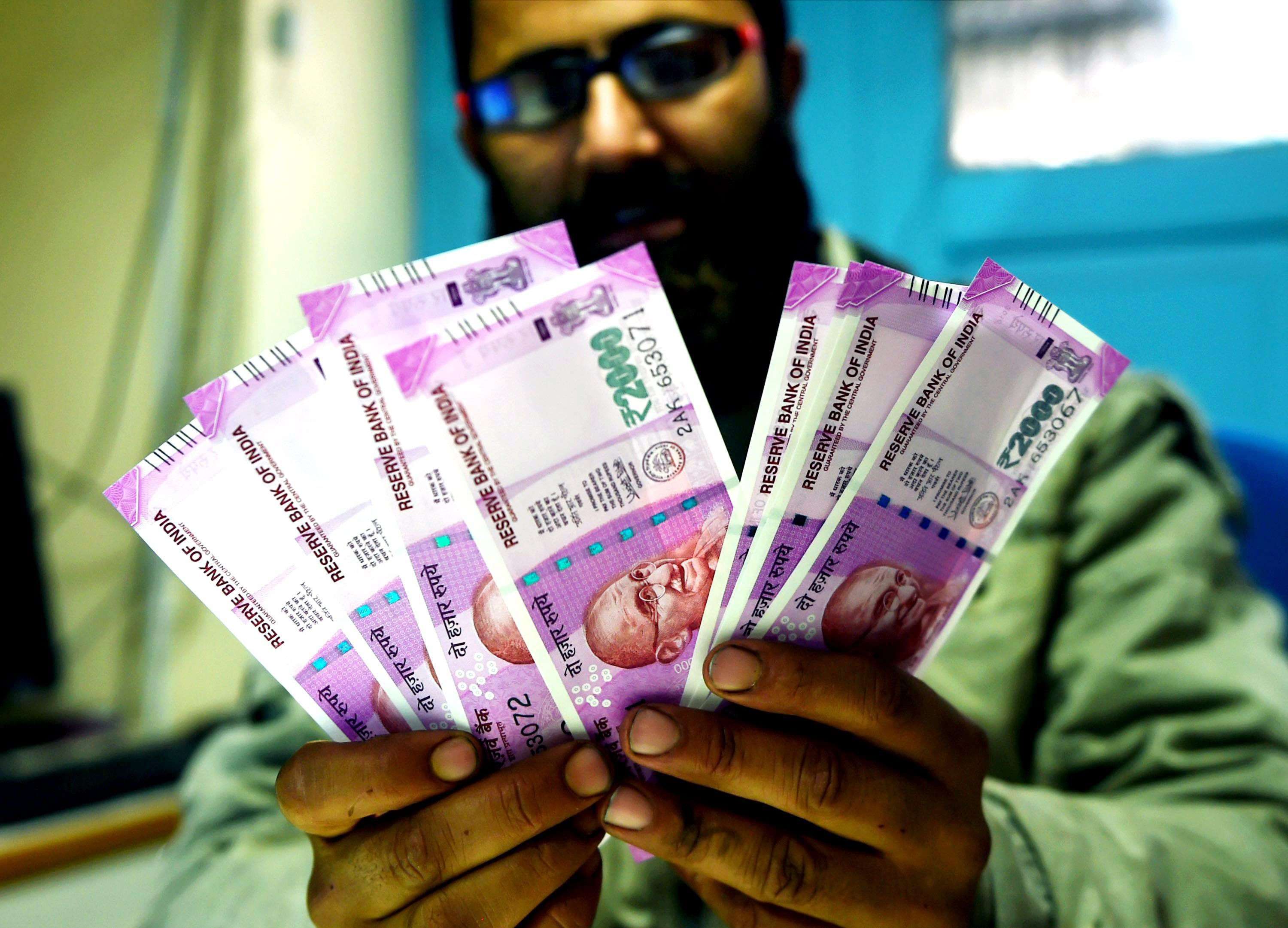 Srinagar: A bank employee counting new Rs 2000 notes before issuing to the customers in Srinagar on Thursday. PTI Photo by S Irfan(PTI11_10_2016_000222B)