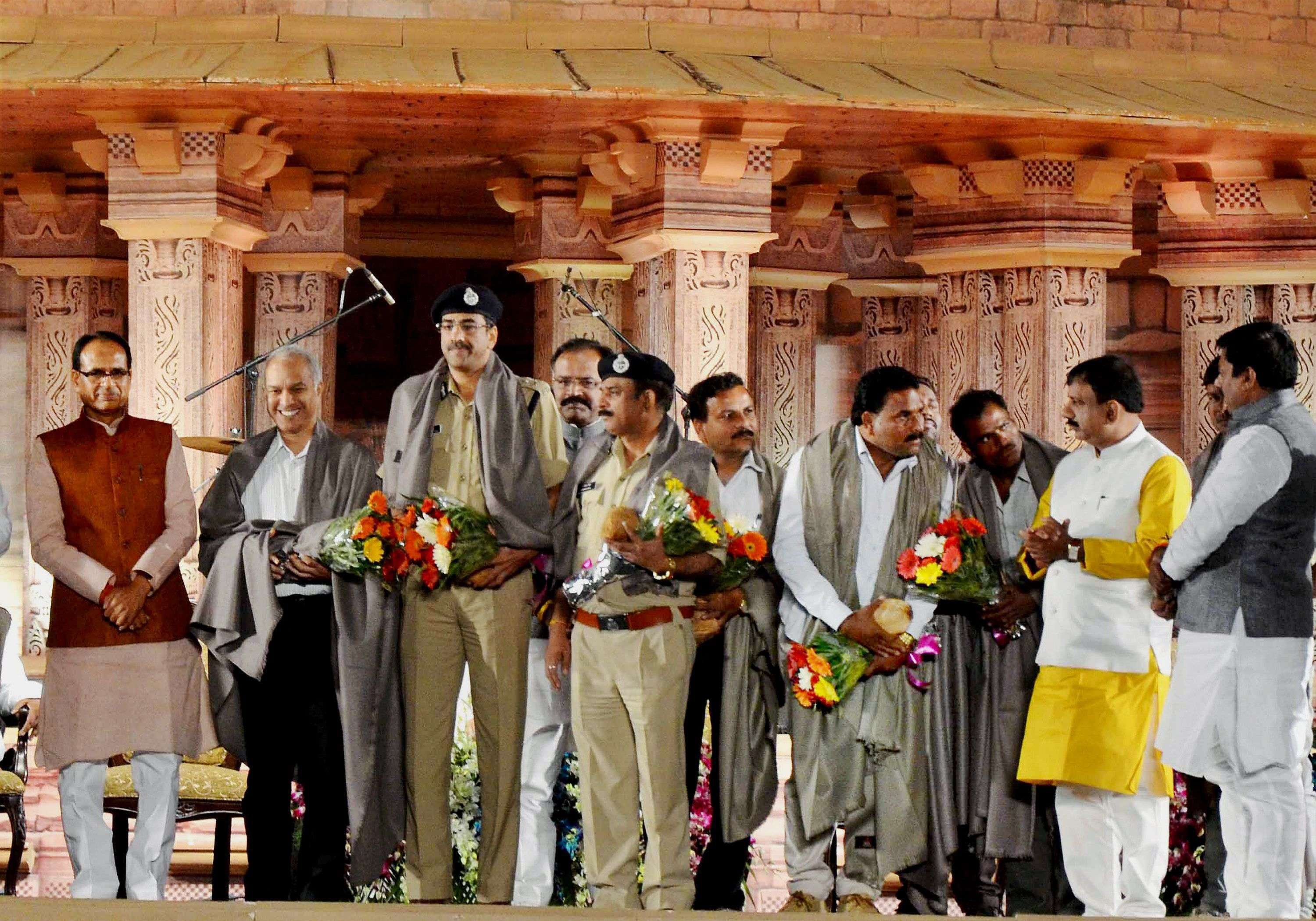 Bhopal: Madhya Pradesh Chief Minister Shivraj Singh Chouhan felicitates police officers and STF personnel who played key role in an encounter to kill SIMI terrorists who escaped from jail, during 61st Madhya Pradesh foundation day programme in Bhopal on Tuesday. PTI Photo(PTI11_2_2016_000032B)