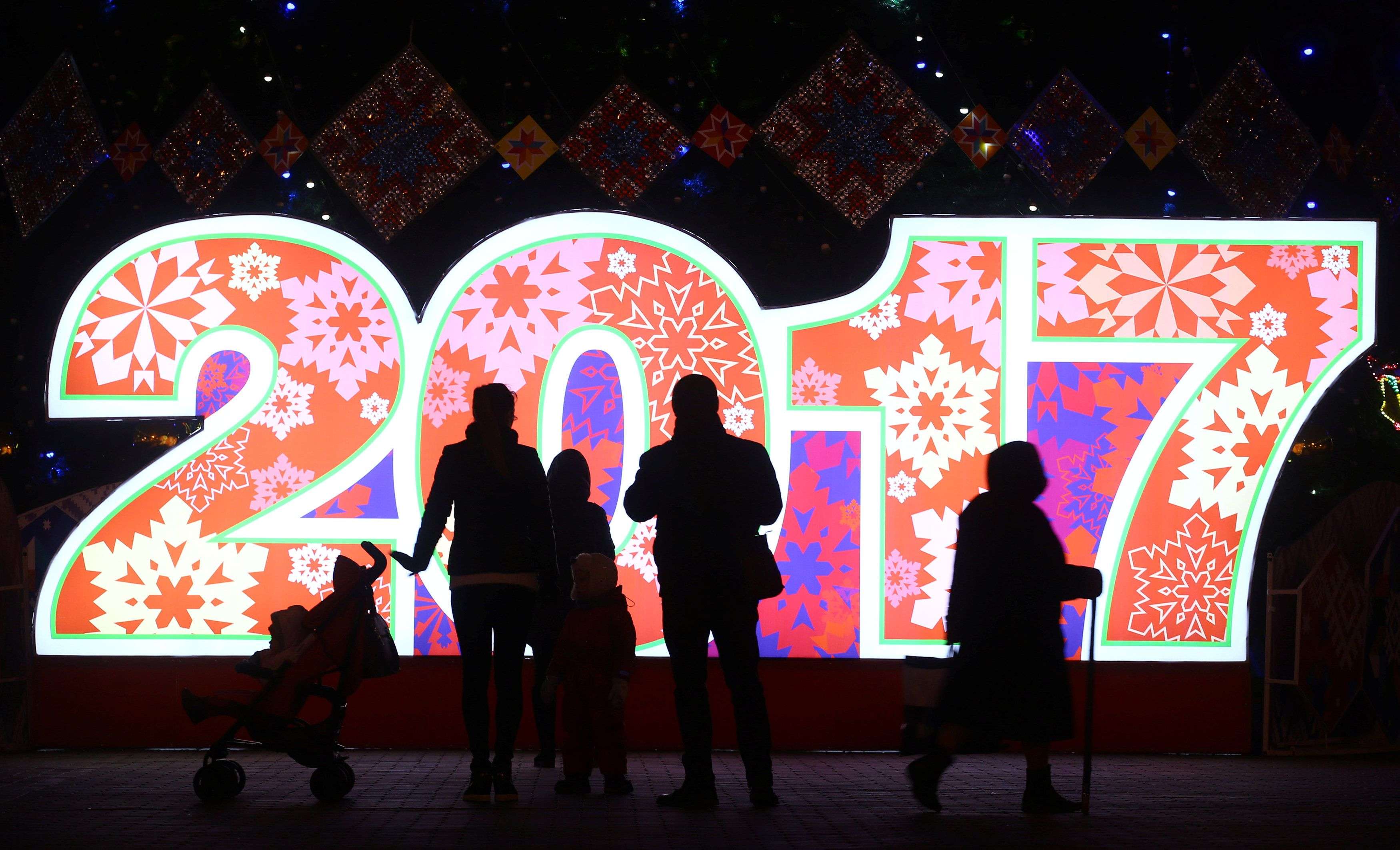 People are seen in front of big numbers reading 2017 at Oktyabrskaya Square for the upcoming New Year and Christmas season in Minsk