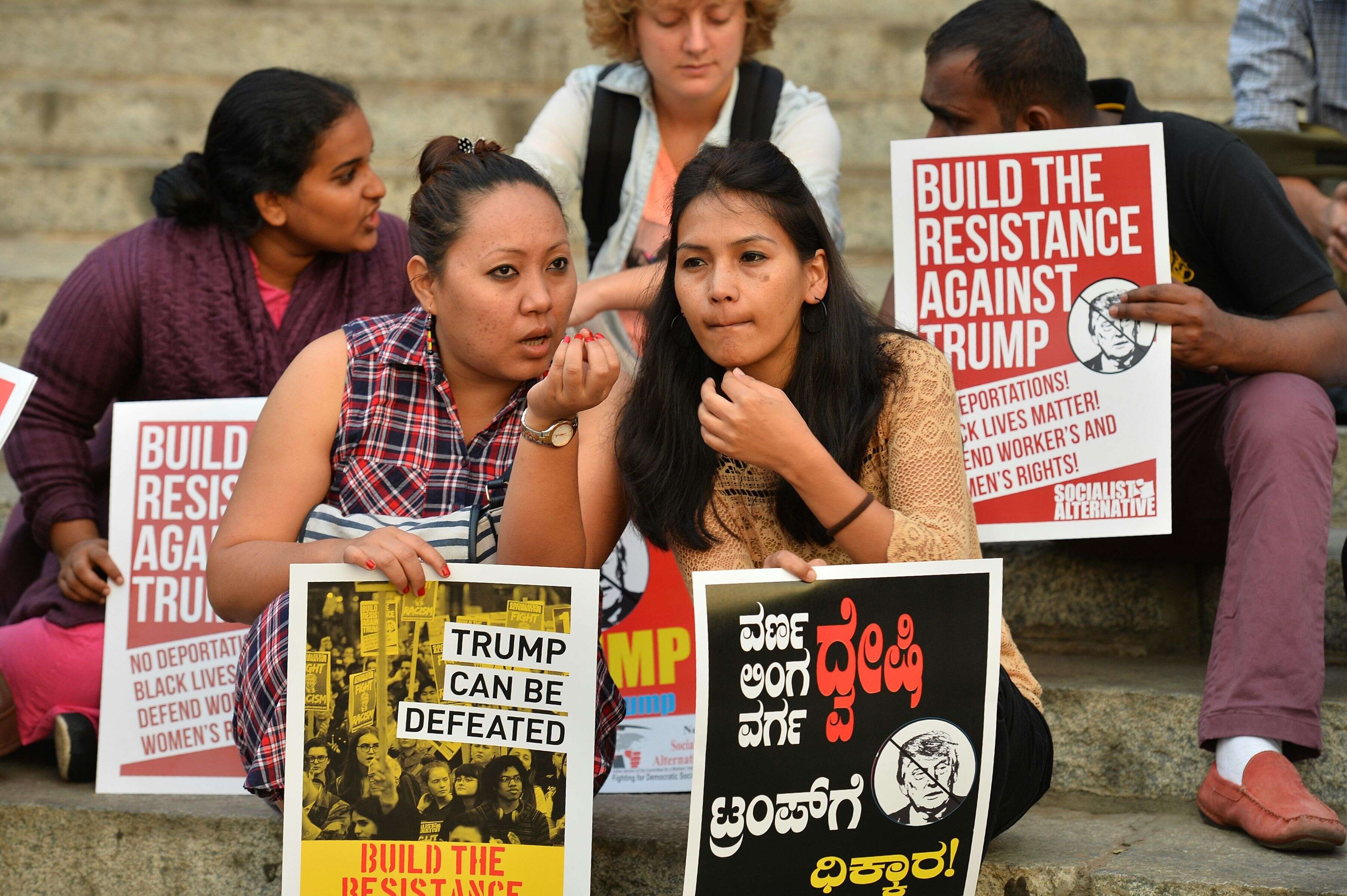 Activists hold placards as they demonstrate against the new US President Donald Trump in Bangalore on January 21, 2017. Demonstrations are taking place in countries around the world along with cities across the United States, a day after Trump's inauguration. / AFP PHOTO / MANJUNATH KIRAN