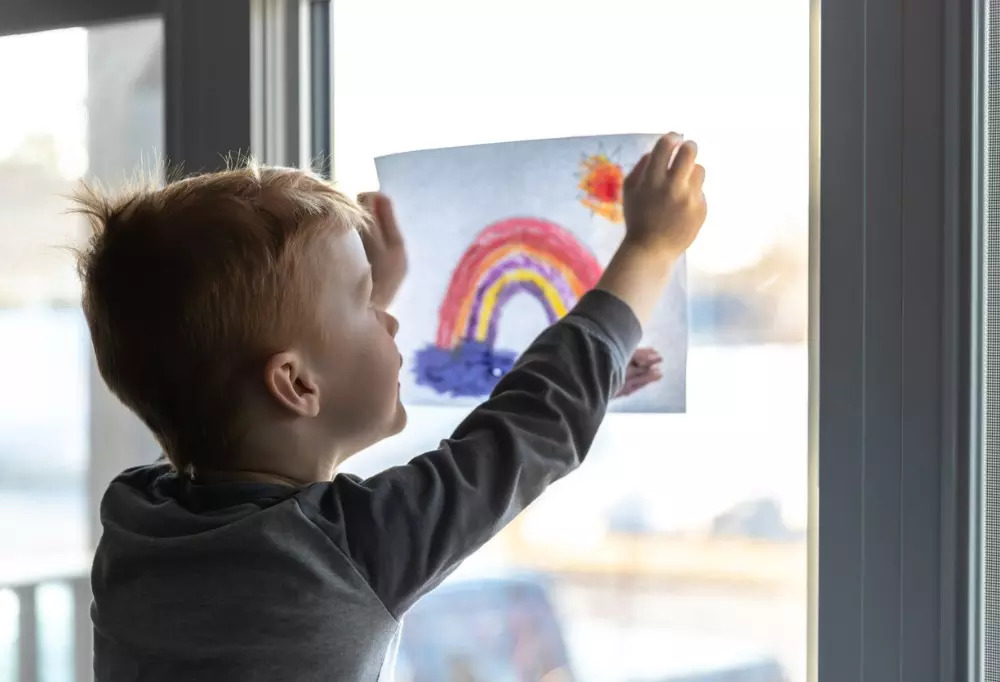 young-boy-sticking-his-drawing-on-home-window-during-the-covid19-picture-id1216065304