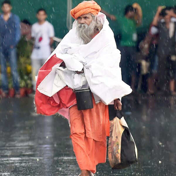 A sadhu walks in rain at Rajpath