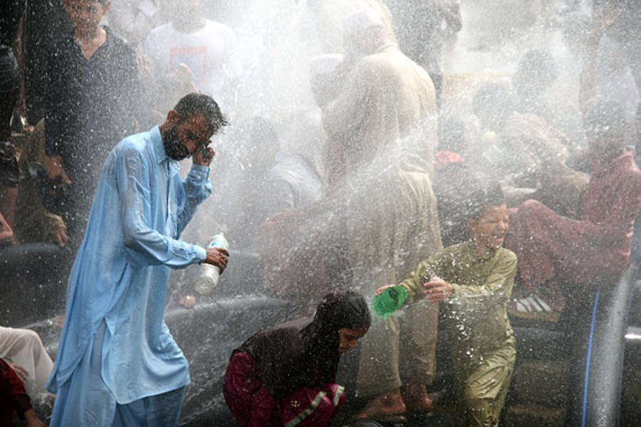 Pakistani people cool off at water supply