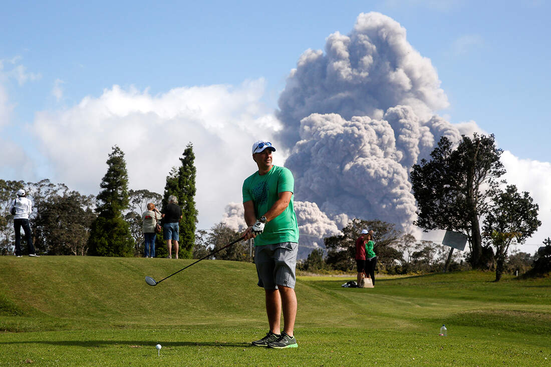Sean Bezecny 46 Of Houston Texas Takes A Golf Swing As Ash Erupts From The Halemaumau Crater Near The Community Of Volcano During Ongoing Eruptions Of The Kilauea Volcano In Hawaii U