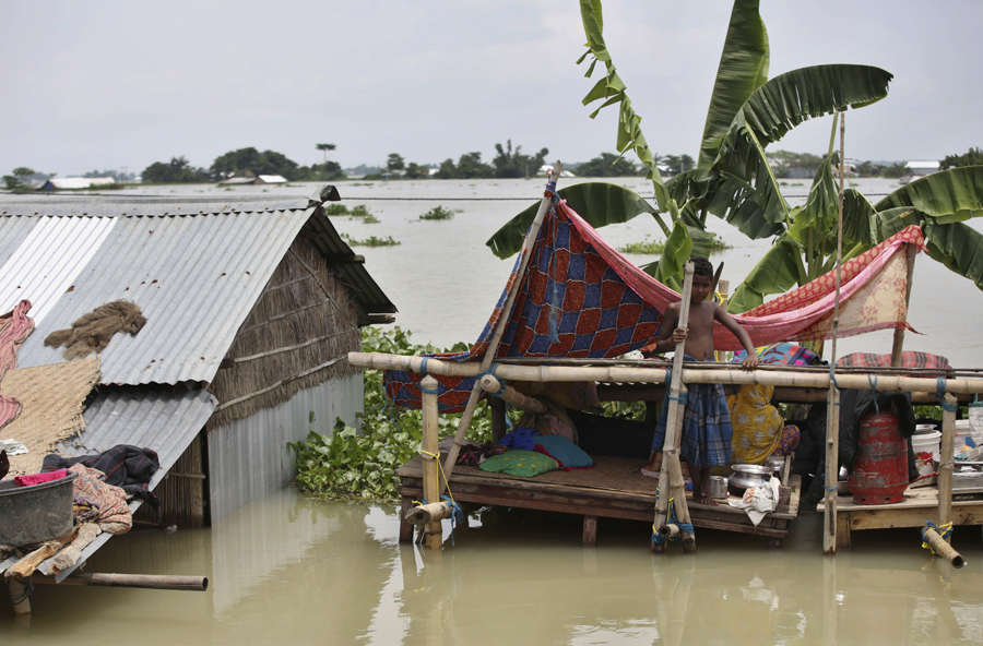 Indian flood affected boy stands on a makeshift platform near his ...