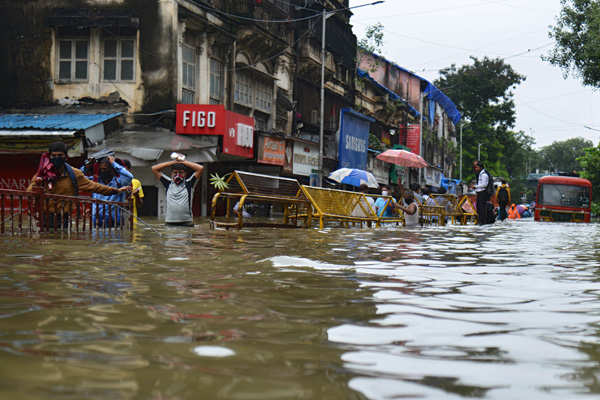 A vendor sells snacks on a handcart in a flooded street following heavy ...