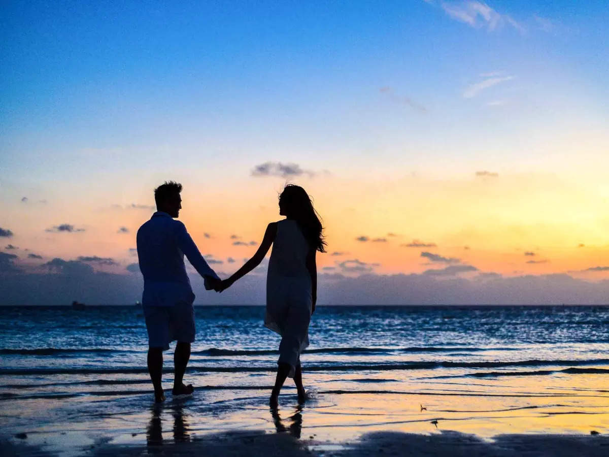 couple taking a stroll on a beach with a sunset view