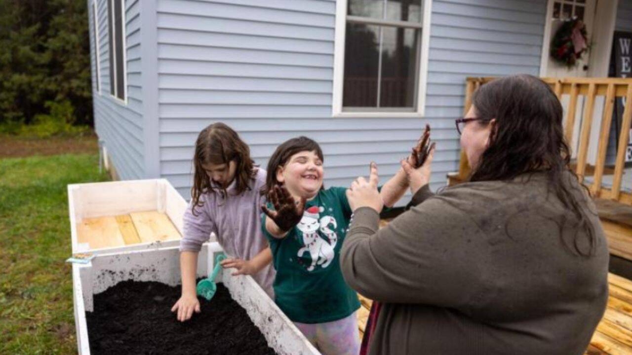 Sarah and her daughters plant vegetable seeds in planter boxes made from 2022 Rockefeller Center Christmas tree lumber.