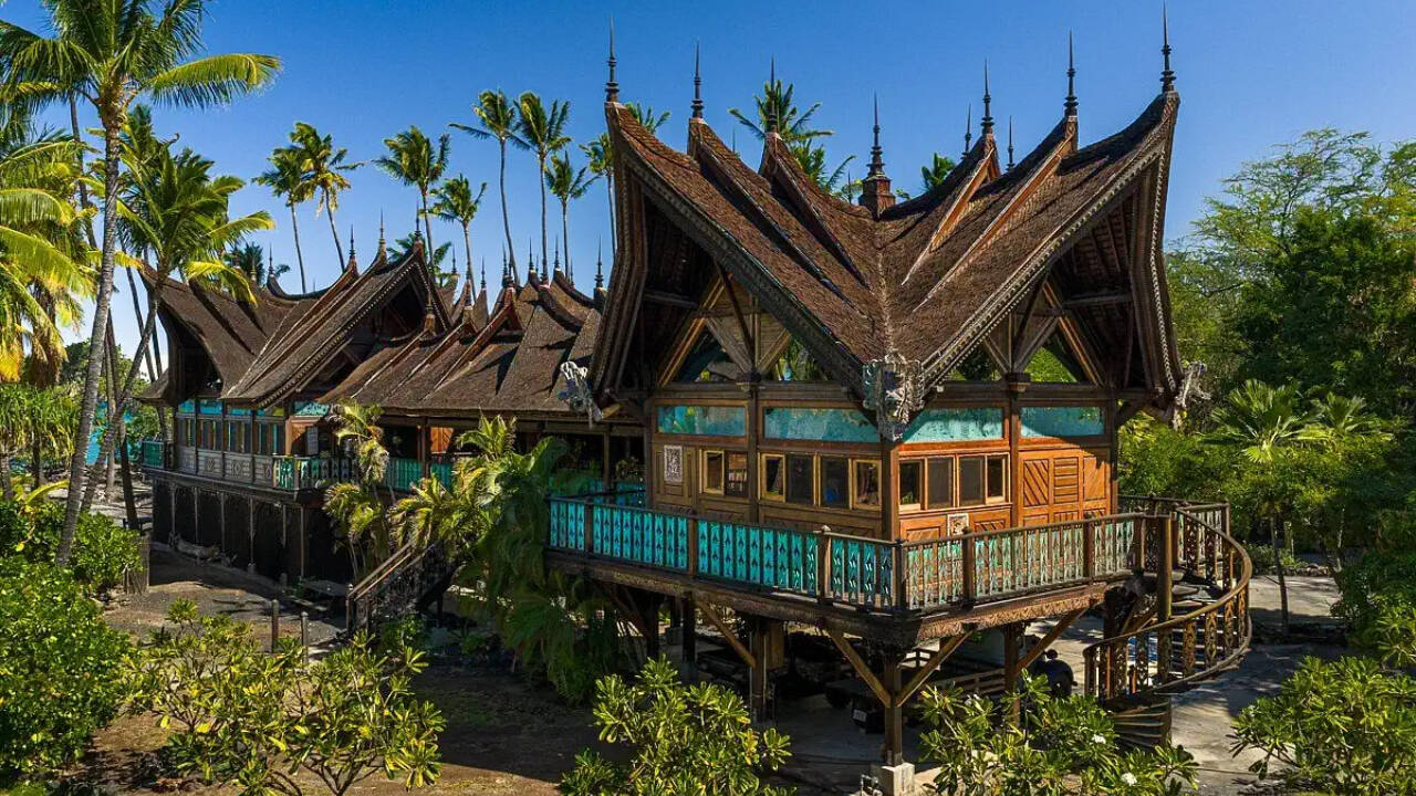 Inside, elaborate Indonesian carvings and traditional features make the property feel like a living museum, while the landscape around it anchors it firmly in Hawaii.