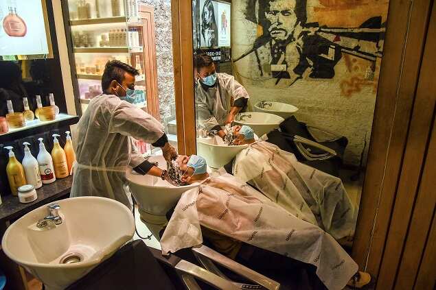 Staff wearing protective gears attend to the customer as the salons reopen following the unlocking guidelines by the Delhi government. (ANI photo)