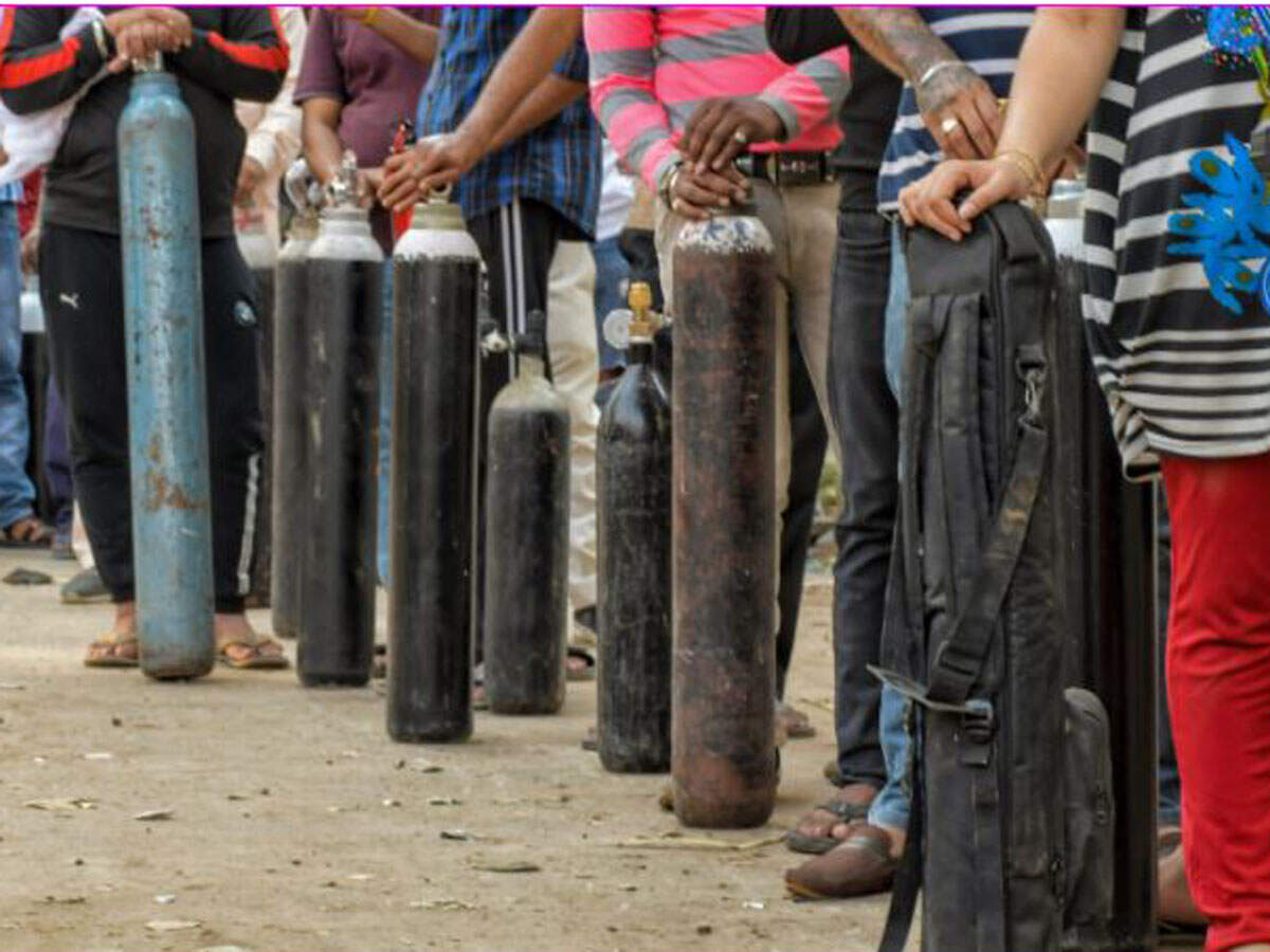 Family members of Covid-19 patients wait outside an oxygen-filling center to refill their empty cylinders, as demand for the gas rises due to spike in coronovirus cases, at Mayapuri in New Delhi, Thursday. PTI