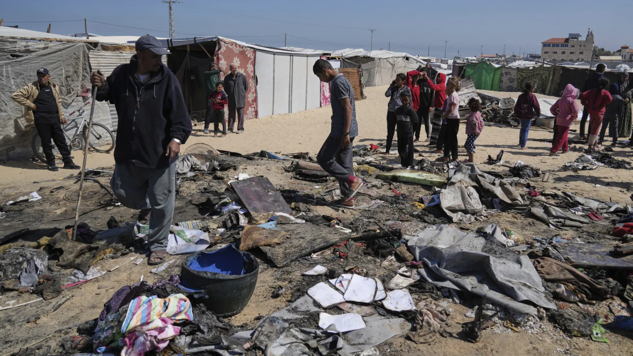Palestinians inspect the remains of a displacement tent hit by an Israeli airstrike overnight