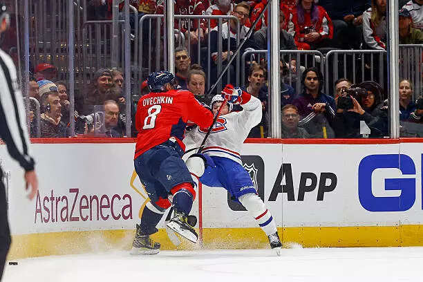 Alex Ovechkin #8 of the Washington Capitals finishes a check against Cole Caufield #13 of the Montreal Canadiens in the second period during Game One