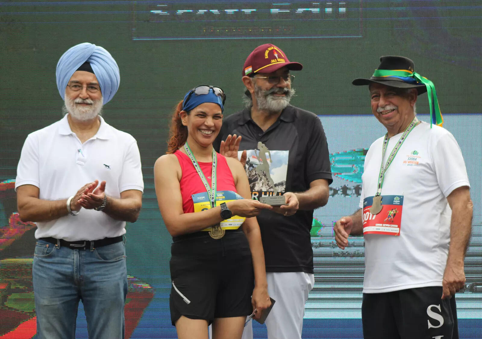 A woman runner who won the 21 Km  run in her age category receiving her trophy and medal.