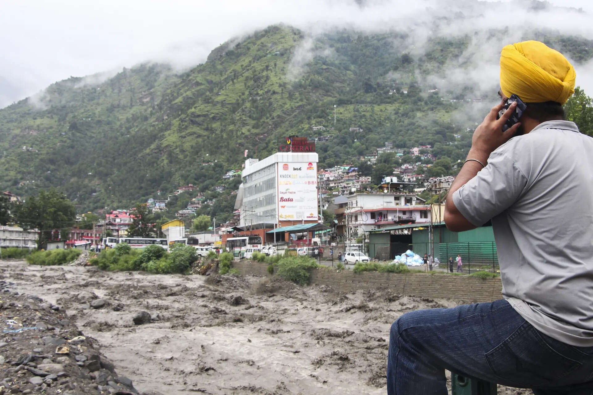 Kullu: A man looks at the muddy water flowing through the Sarvari River following rainfall, in Kullu. (PTI Photo) Sarvari River in Kullu