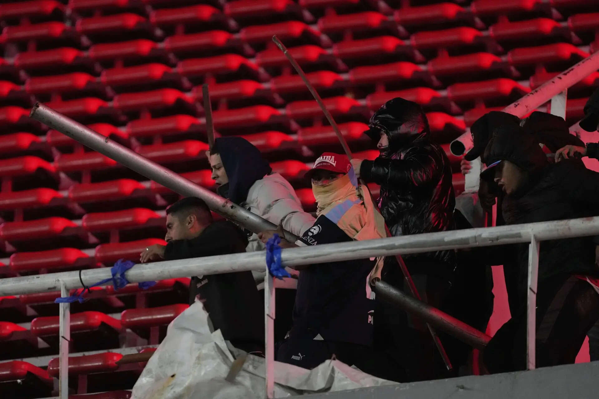 Fans of Argentina's Independiente hold metal bars during clashes with Universidad de Chile fans after a Copa Sudamericana round of sixteen second leg soccer match was suspended at the Libertadores de America stadium in Avellaneda, Argentina, Wednesday, Aug. 20, 2025. (AP Photo/Gustavo Garello) More than 100 Chilean fans arrested after violence in the stands during soccer match in Argentina