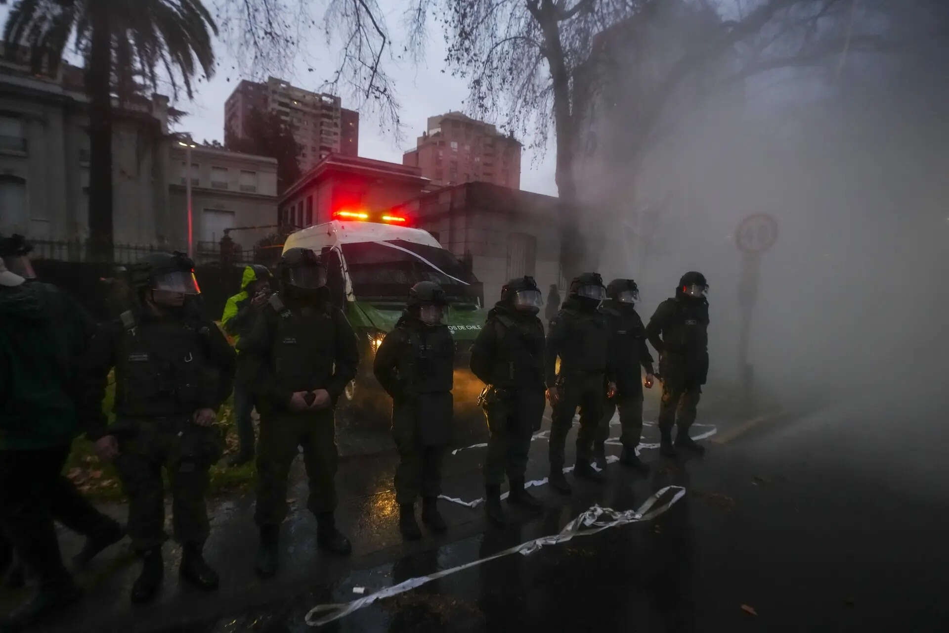 Police office stand guard by the Argentine embassy in Santiago, Chile, Thursday, Aug. 21, 2025, as people protest a day after clashes broke out between Universidad de Chile fans and those of Argentina's Independiente at a Copa Sudamericana soccer match in Buenos Aires. (AP Photo/Esteban Felix) Chile Argentina Copa Sudamericana