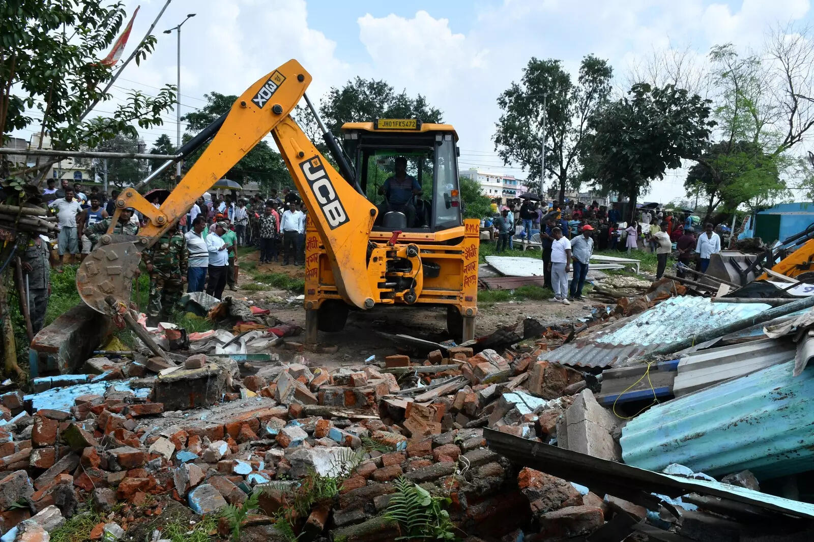An excavator razes homes in Birsa Chowk on Saturday