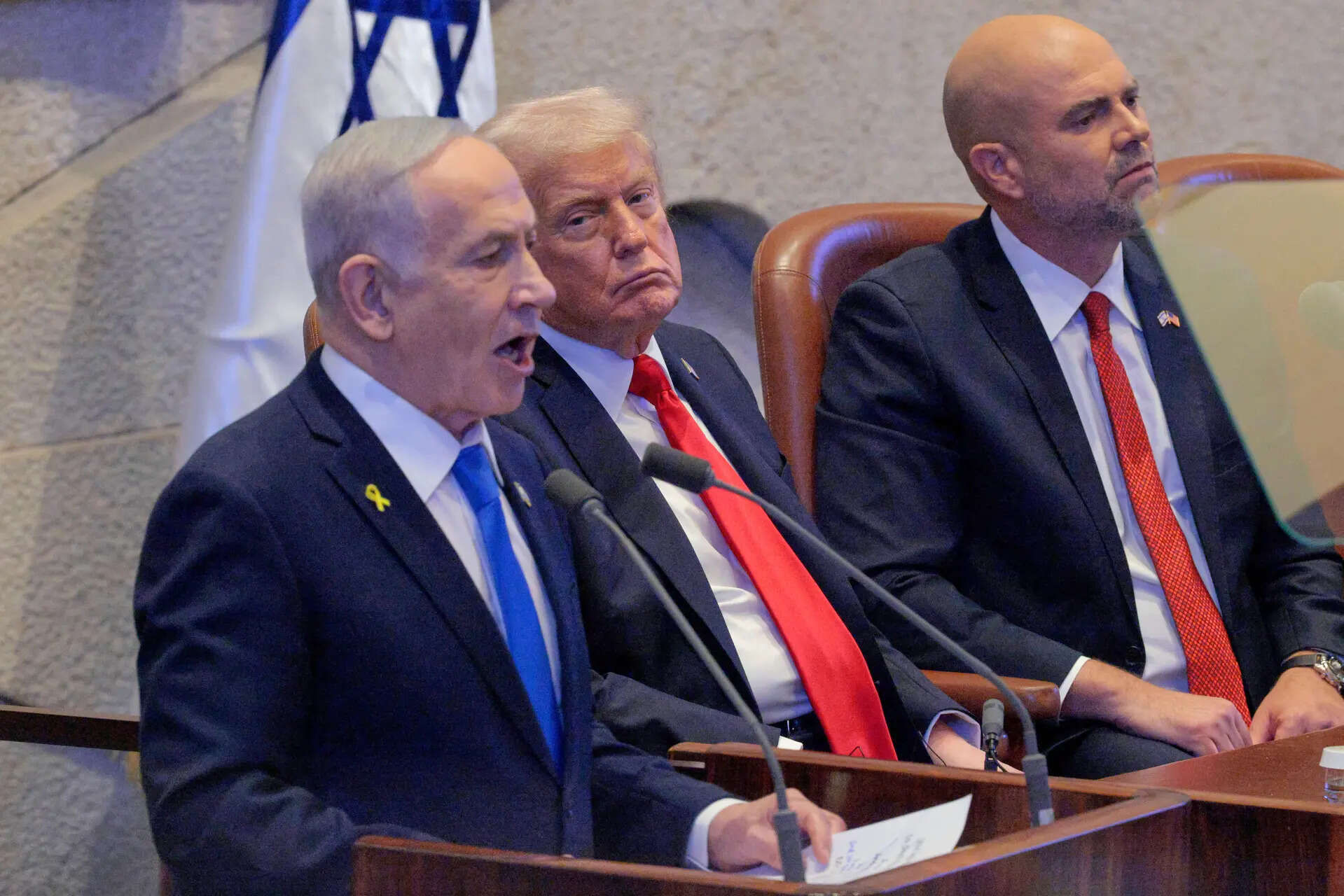 Israeli Prime Minister Benjamin Netanyahu addresses the Knessett, Israel's parliament, as President Donald Trump and Amir Ohana, Speaker of the Israeli Knesset, look on, Monday, Oct. 13, 2025, in Jerusalem. (Chip Somodevilla/Pool via AP) Trump Mideast Wars Gaza