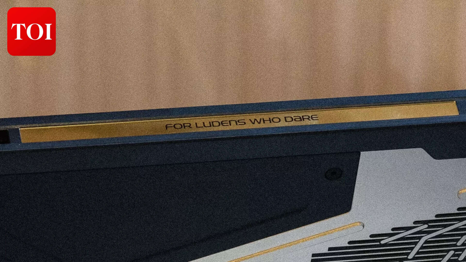 "FOR LUDENS WHO DARE" etched into the gold strip along the top edge. ROG's motto, Kojima-fied