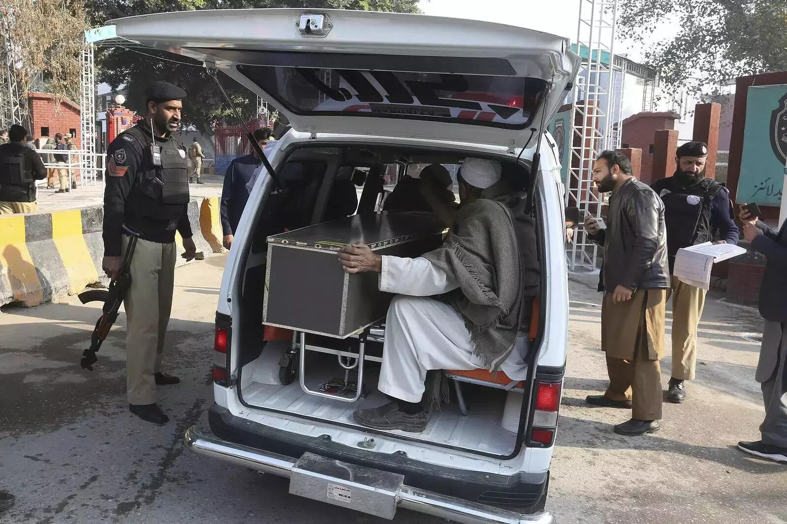 Police officers check a vehicle transporting the body of a police officer killed....