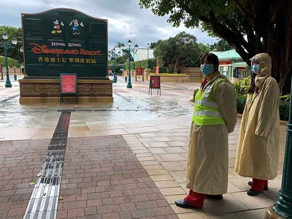 Employees wearing protective masks stand outside the Hong Kong Disneyland theme park that has been closed, following the coronavirus outbreak, in Hong Kong