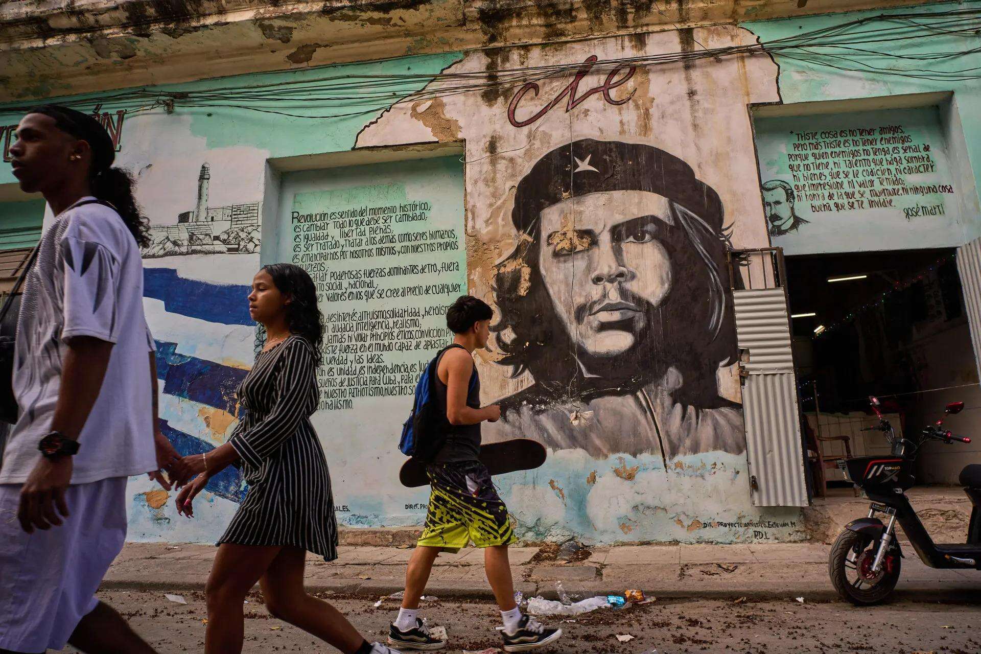 People walk past a mural depicting Ernesto “Che” Guevara