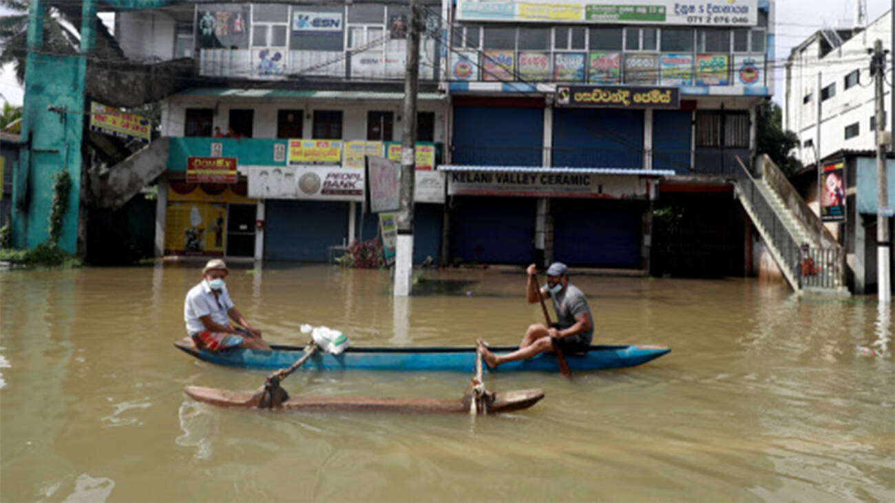 Devastating effects of Sri Lanka flood: Men floating along a flooded road in Biyagama, Sri Lanka