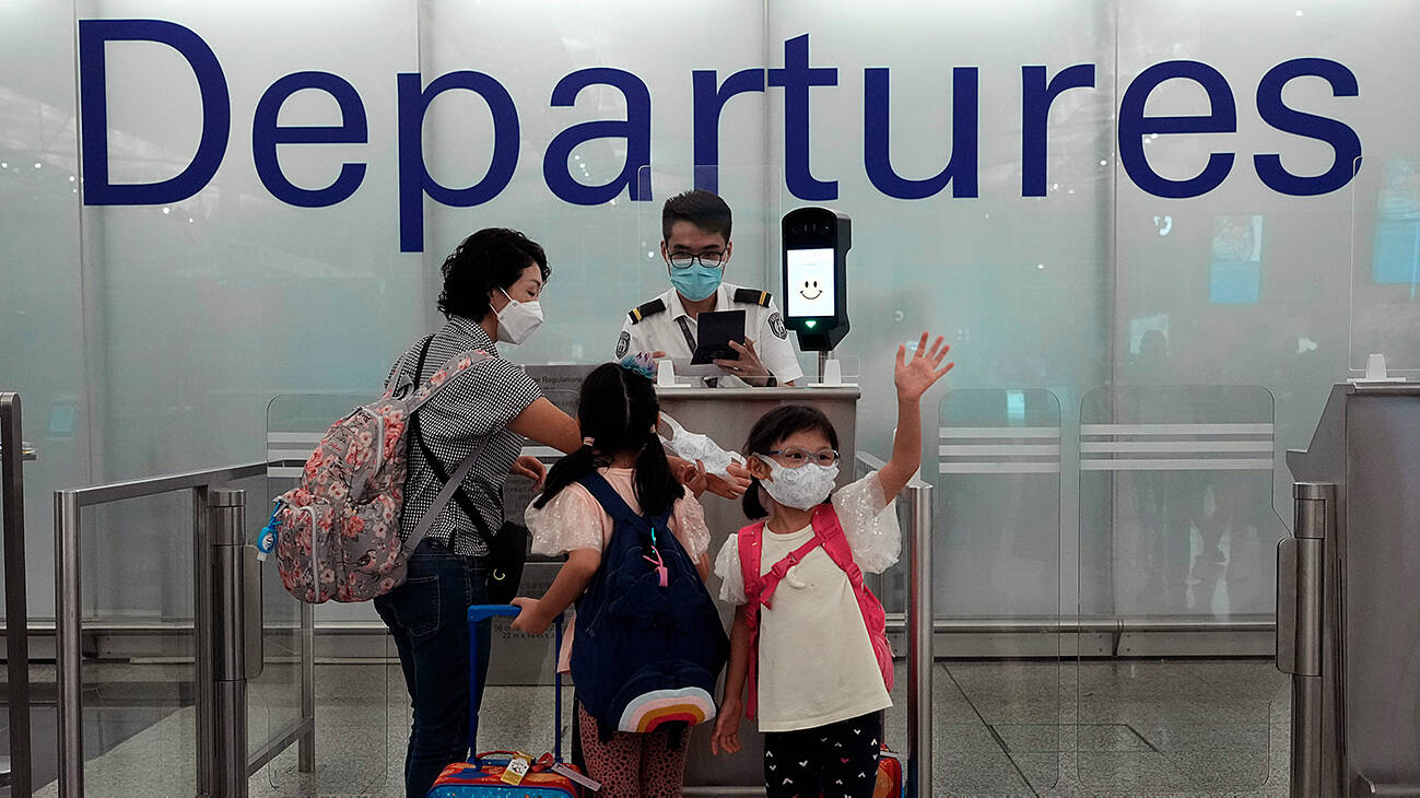 A girl waves farewell to friends as she departs for a permanent move to the UK at the Hong Kong airport. (Photo Credit: AP)