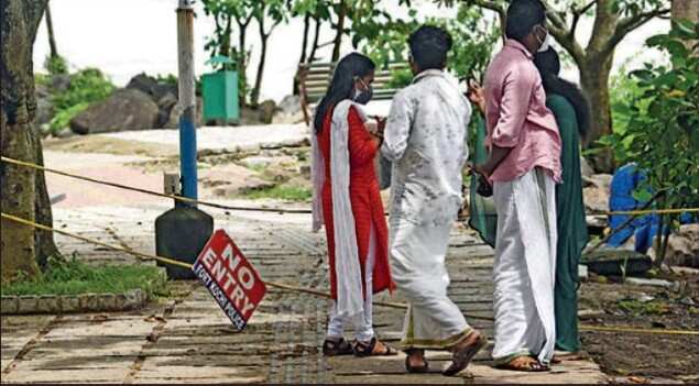 Visitors stand at the entry point to the walkway at Fort Kochi beach on Friday, which remains closed. Many people have started visiting Fort Kochi with the lockdown restrictions eased