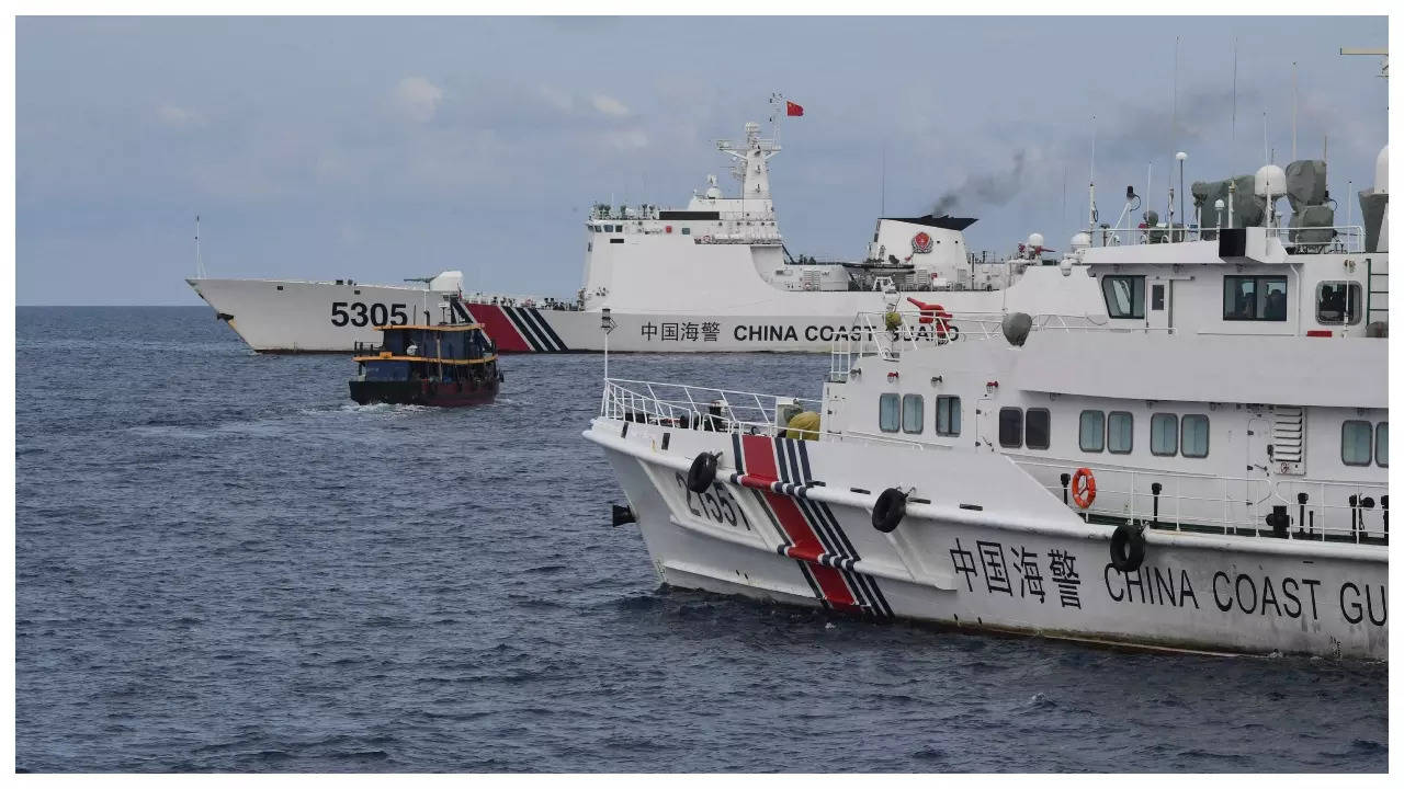 Chinese coast guard ships (L & R) corralling a Philippine civilian boat in the disputed South China Sea in August 2023. (AFP photo)
