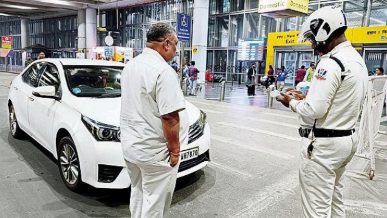 A cop issues a fine against a car for staying parked on a zebra crossing in front of one of the gates of the arrivals terminal