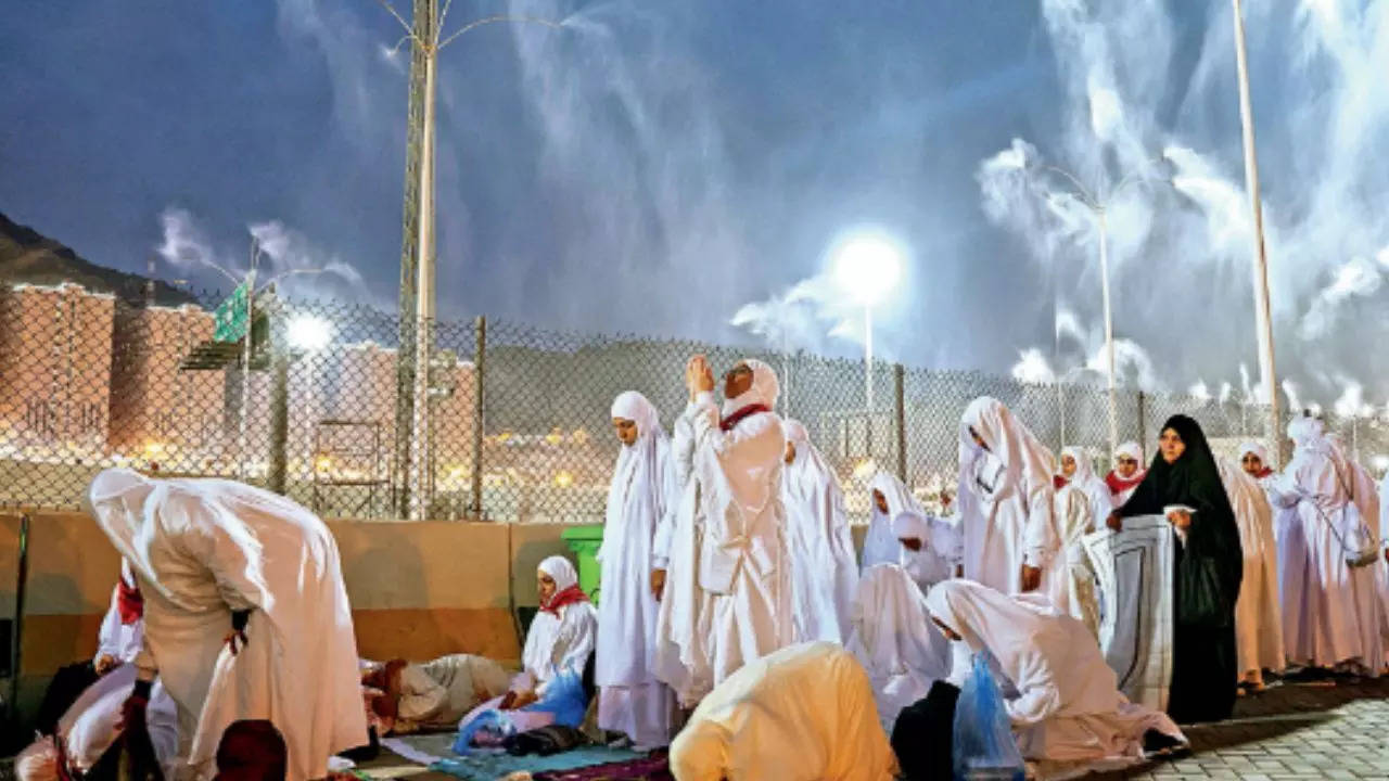 Muslim pilgrims pray while sprinklers cool them down during the annual Haj pilgrimage, on Thursday